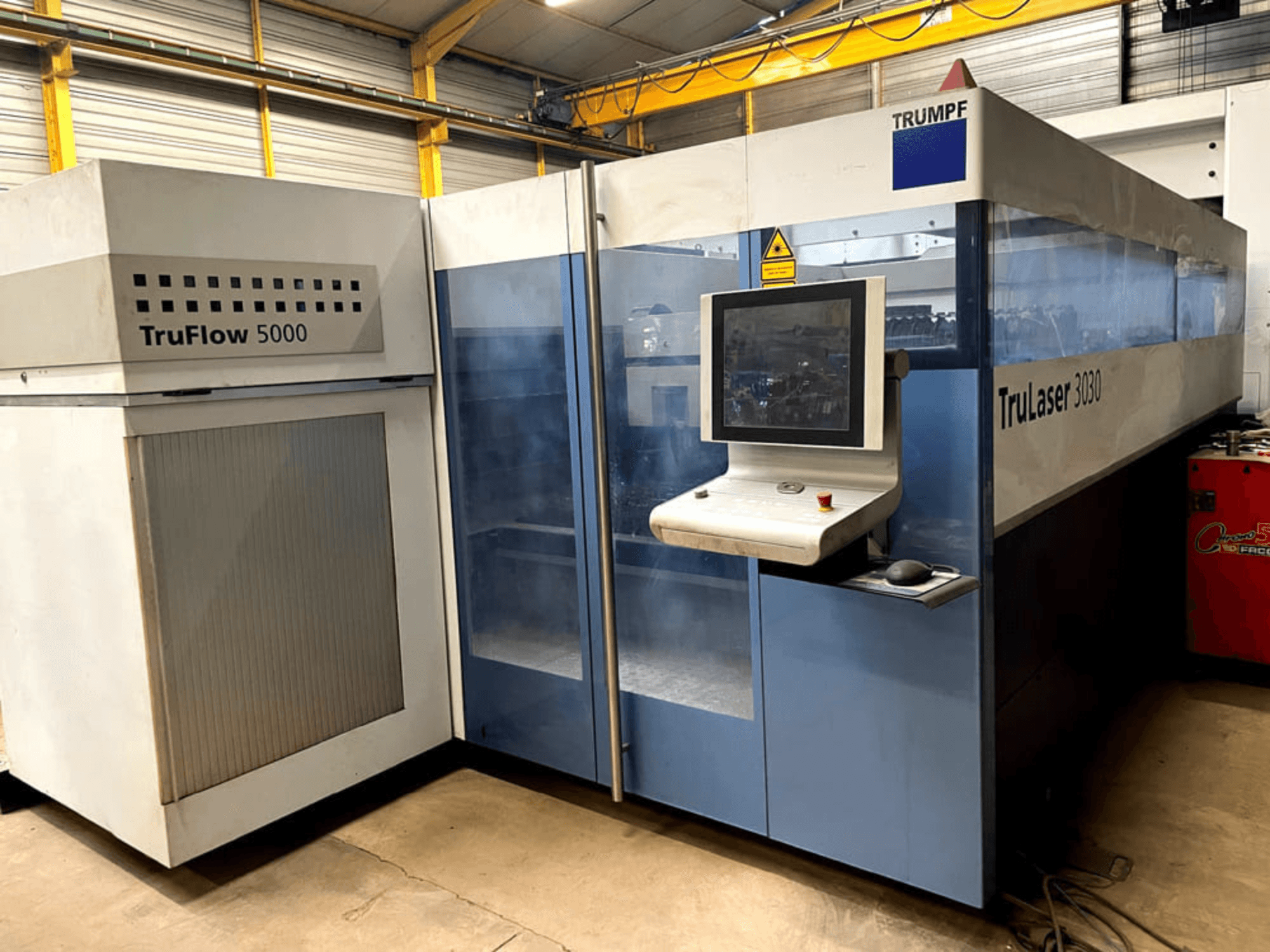 CO₂ laserový řezací stroj TRUMPF TruLaser 3030 v čelním pohledu, s ovládacím panelem a přilehlou jednotkou TruFlow 5000.