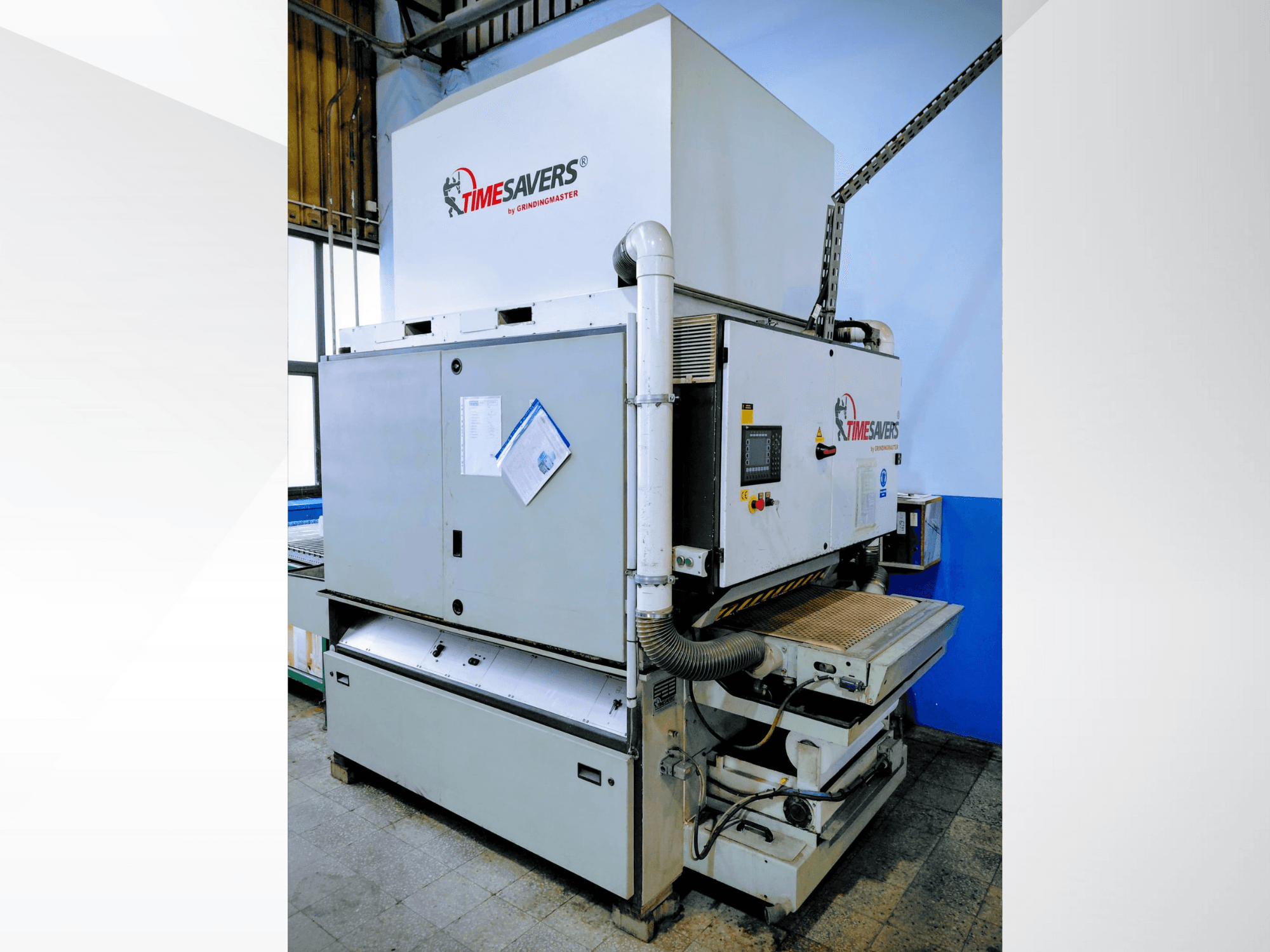 Průmyslová bruska Timesavers, pohled zepředu. Je vybavena provozními ovládacími prvky, odsáváním prachu a nastavitelným brusným ložem pro přesné broušení.