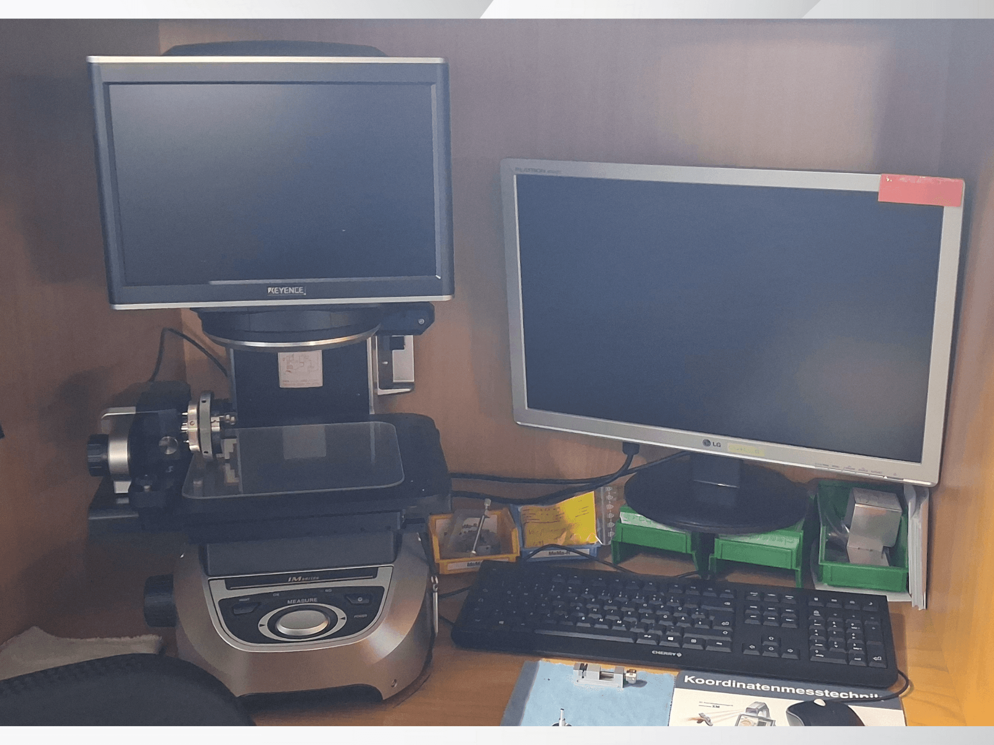 Měřicí systém Keyence se dvěma monitory (jeden LG, jeden Keyence) a klávesnicí, pohled zepředu.