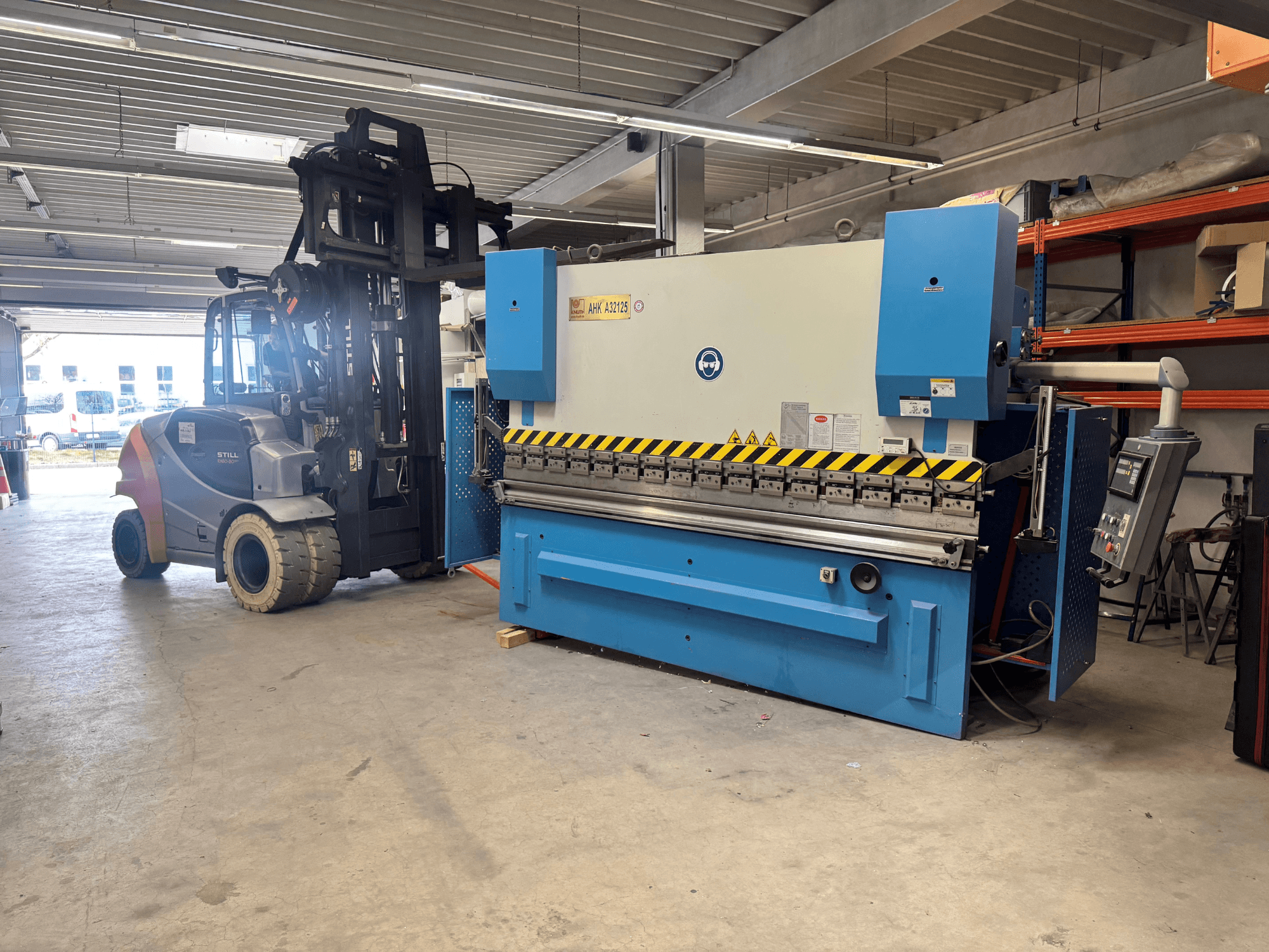 Hydraulický lis KNUTH AHK A 32125 v dílně, boční pohled na ovládací panel a bezpečnostní prvky.
