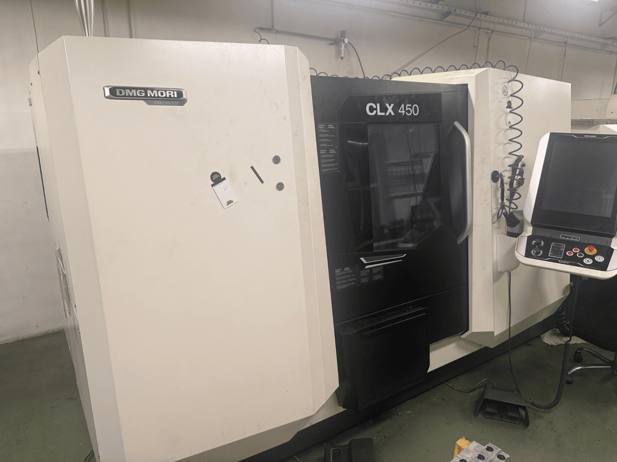Stroj DMG MORI CLX 450 CNC, boční pohled s ovládacím panelem, viditelnými ovládacími tlačítky a čistým pracovním prostorem.