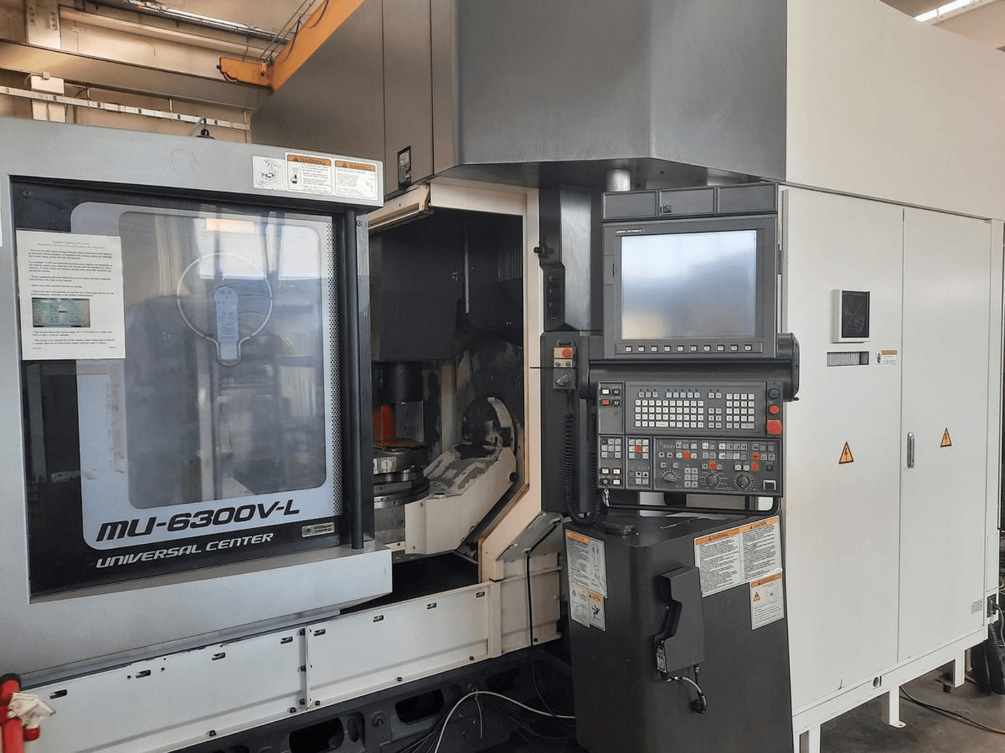 Stroj MU-6300V-L Universal Center zobrazený zepředu, s viditelným ovládacím panelem, obrazovkou a návodem k obsluze.