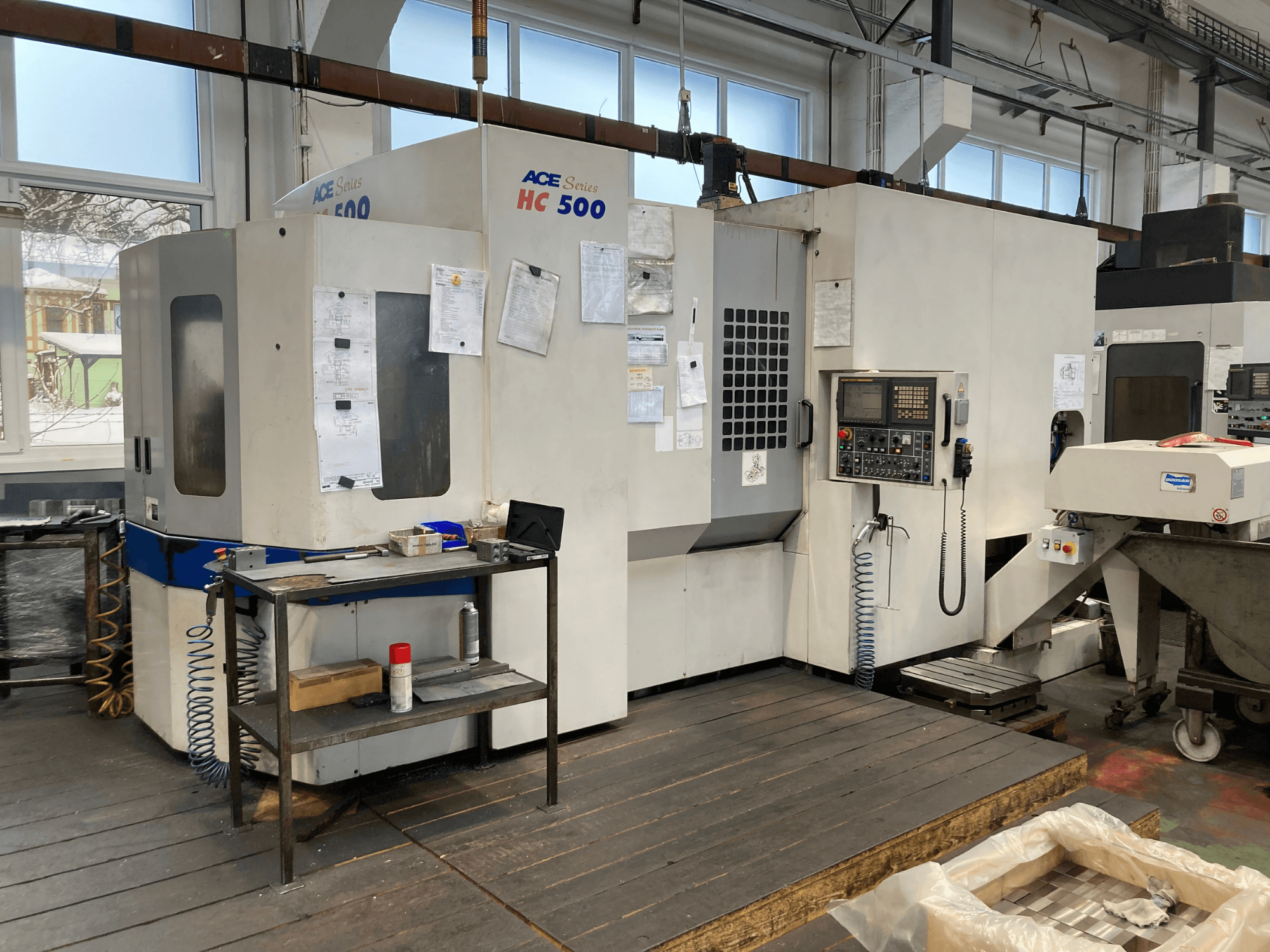 Horizontální obráběcí centrum DOOSAN ACE HC-500, pohled zepředu; ovládací panel, více úložných prostorů pro nástroje a průmyslové nastavení.