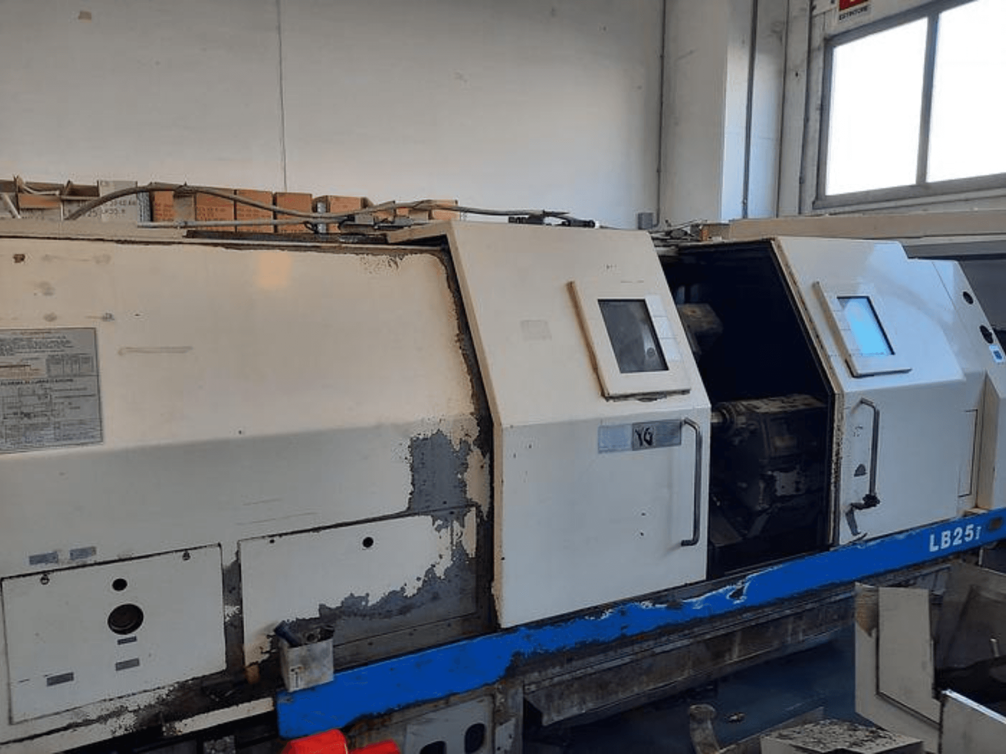 Použitý soustruh LB251, boční pohled ukazuje opotřebovaný exteriér, otevřený panel odhaluje vnitřní mechanismus a ovládací prvky.