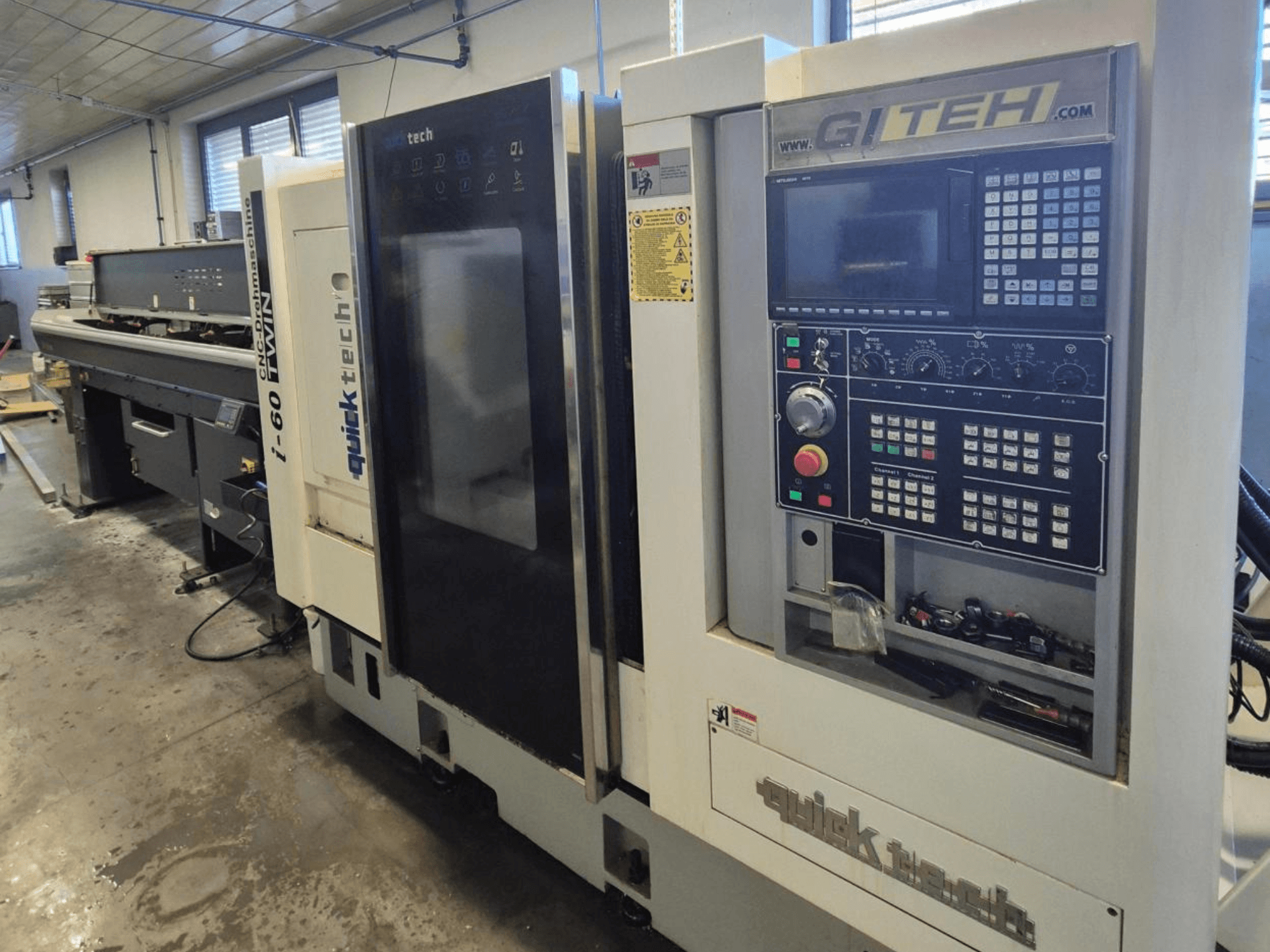 Dvojitý CNC stroj Quick Tech i-60, pohled zepředu, s ovládacím panelem GITEH a ovládacími tlačítky, v dílenském prostředí.