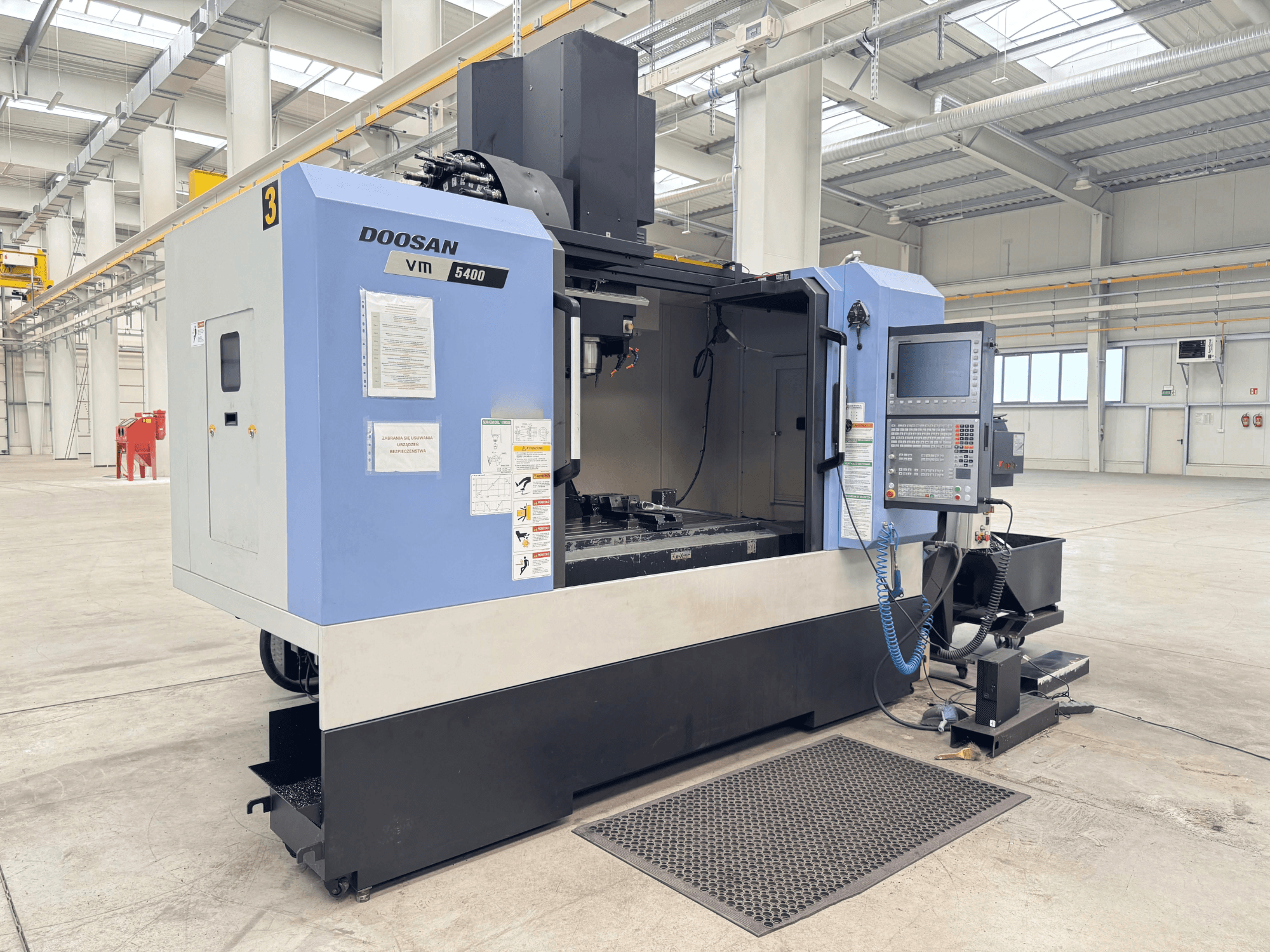 Vertikální obráběcí centrum DOOSAN VM 5400, čelní pohled na ovládací panel a pracovní plochu v prostorném průmyslovém prostředí.