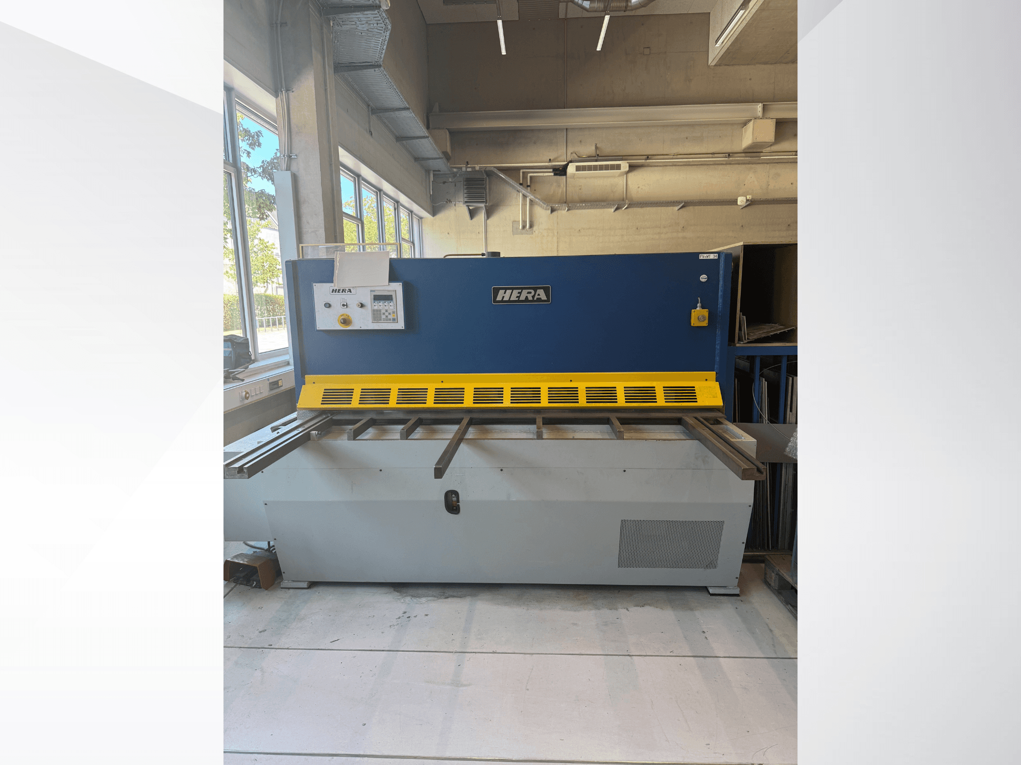 Hydraulické nůžky HERA TS 2000x6 v čelním pohledu, v modro-žlutém provedení s ovládacím panelem a řezacím stolem.