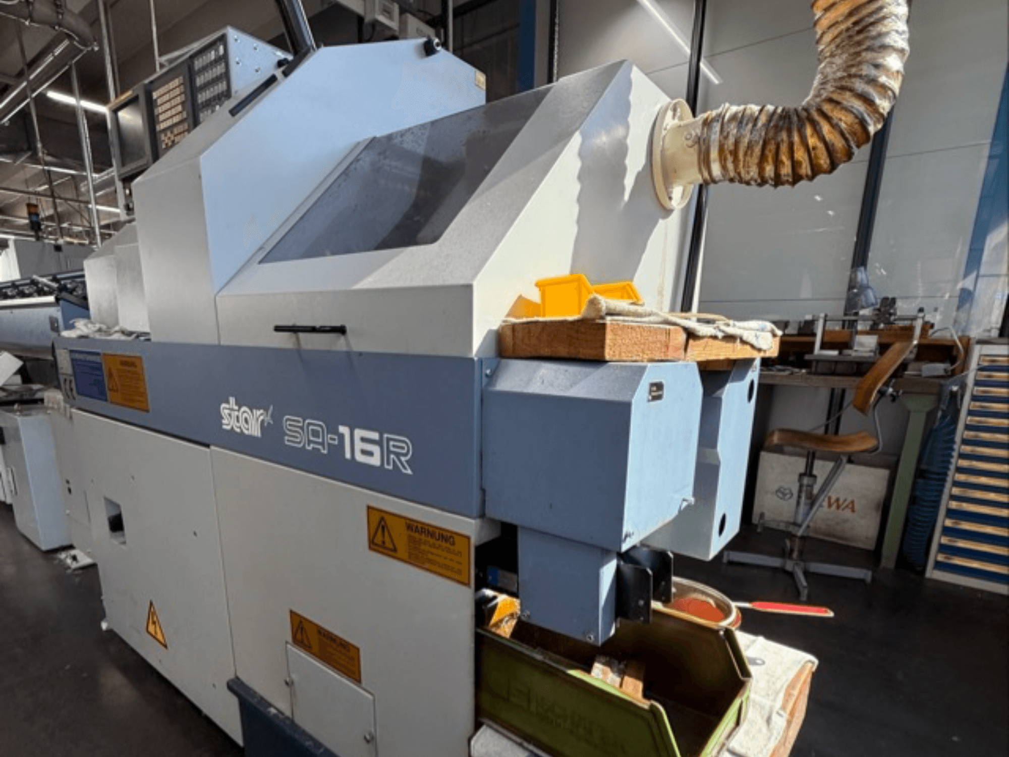 Stroj Stark SA-16R při pohledu zepředu, se zúženým výfukem a pracovním prostorem se žlutými nářadím a výstražnými štítky.