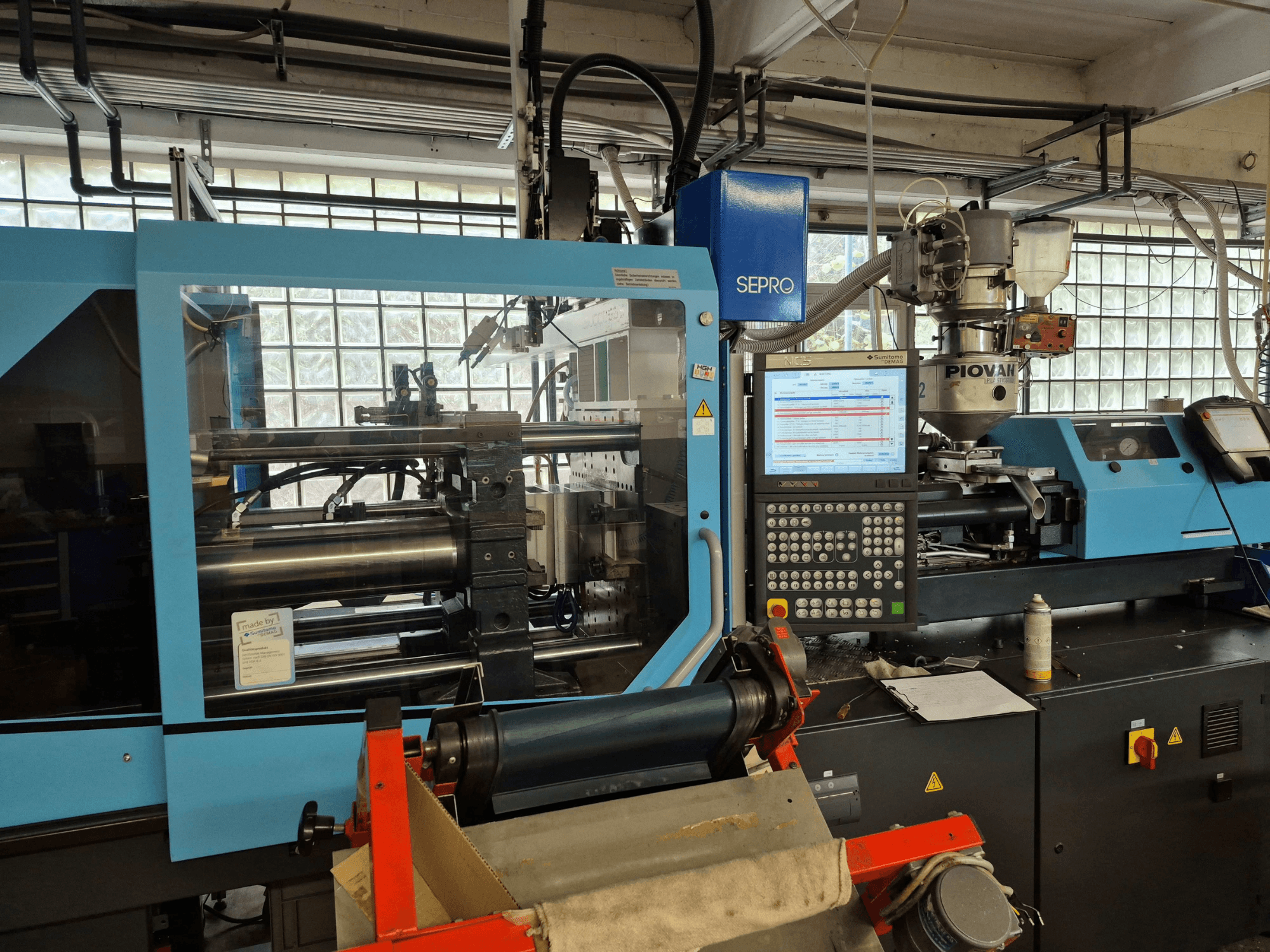 Hydraulický vstřikovací lis SUMITOMO SHI DEMAG Systec 120/470-430, pohled zepředu s viditelným ovládacím panelem a podávacím systémem.