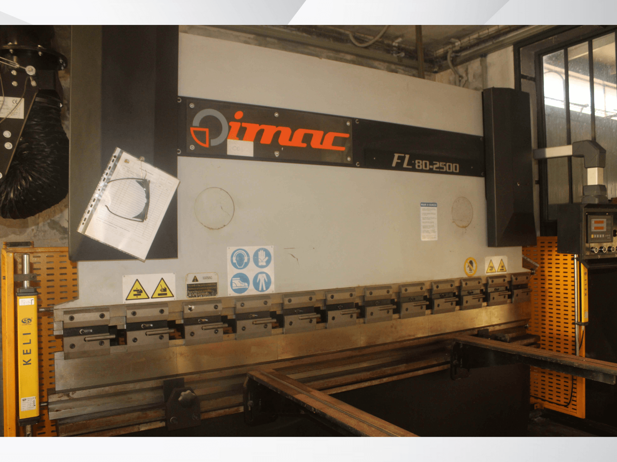 Ohýbačka IMAC FL 80-2500, pohled zepředu, s ovládacím panelem, bezpečnostními upozorněními a součástmi kovového nářadí.