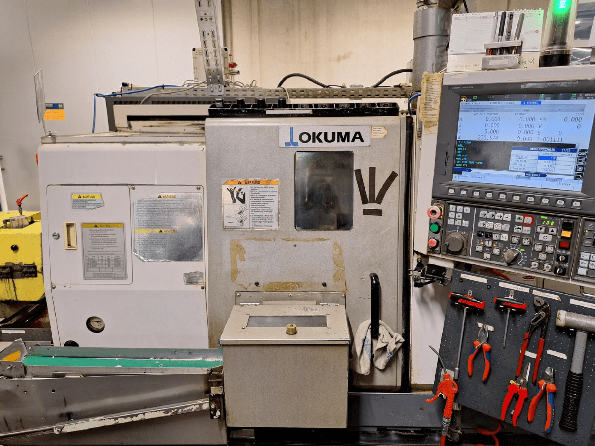 Horizontální soustruh Okuma LB200-MW, pohled zepředu, s ovládacím panelem a nástroji viditelnými z boku.