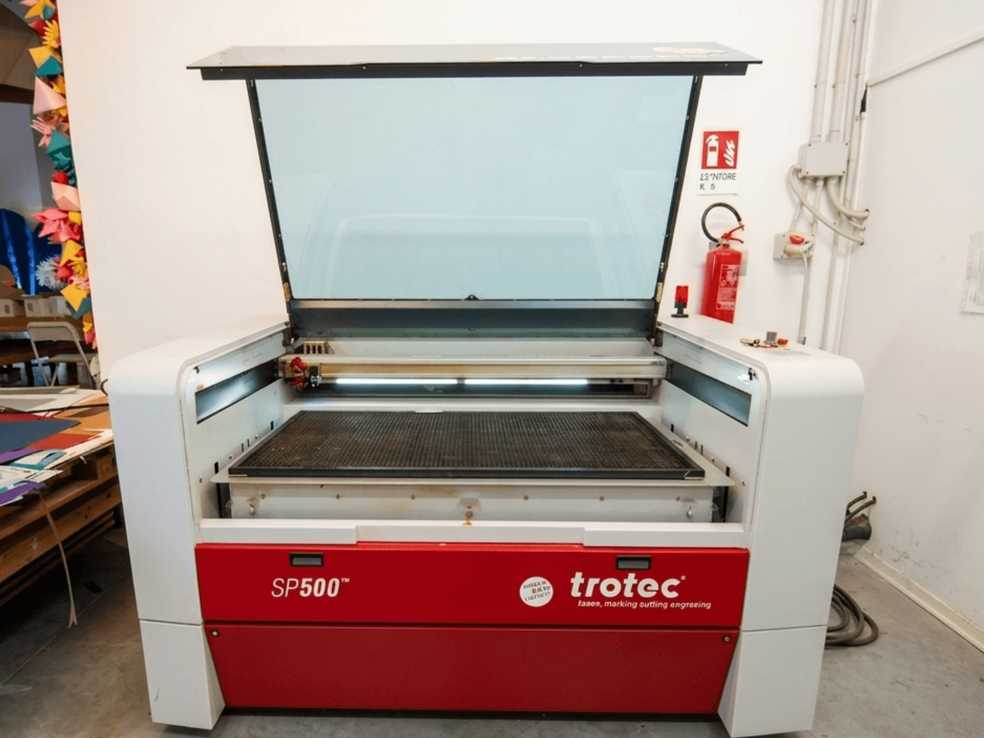 Laserový gravírovací stroj Trotec SP500 C200 v čelním pohledu s otevřeným víkem, na kterém je vidět pracovní plocha a ovládací prvky.