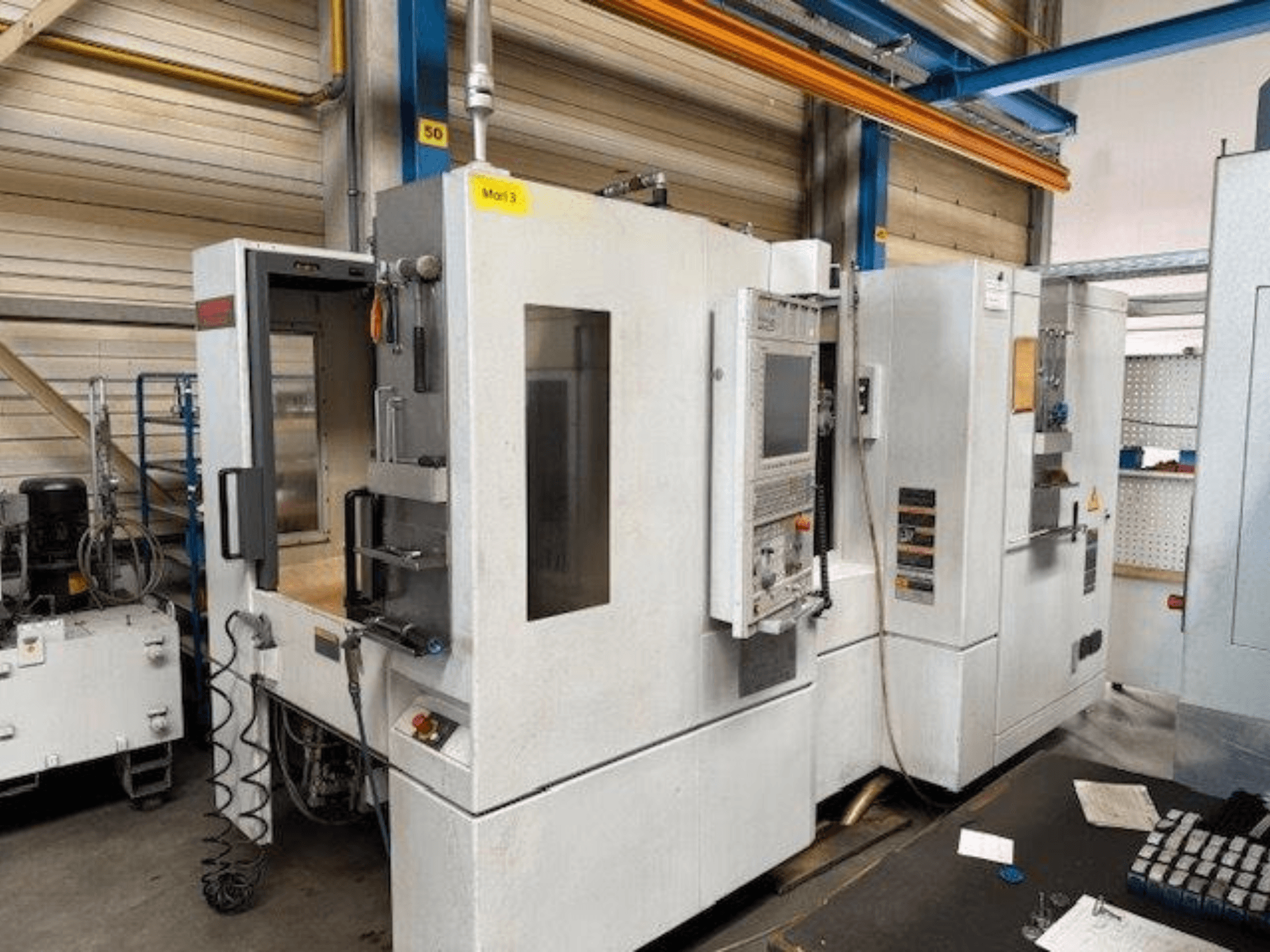 Pohled zepředu na horizontální obráběcí centrum MORI SEIKI NH4000 DCG s otevřenými dveřmi a viditelným ovládacím panelem, který ukazuje provozní prostor.