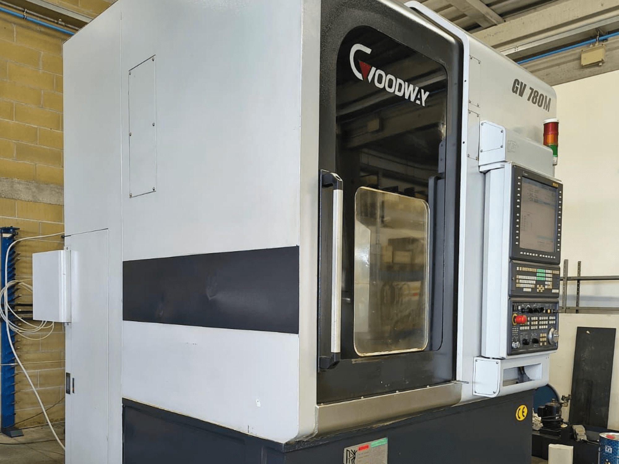 Vertikální soustruh Goodway GV 780 M, boční pohled, ukázka ovládacího panelu, bezpečnostních prvků a čistého vnějšího designu.