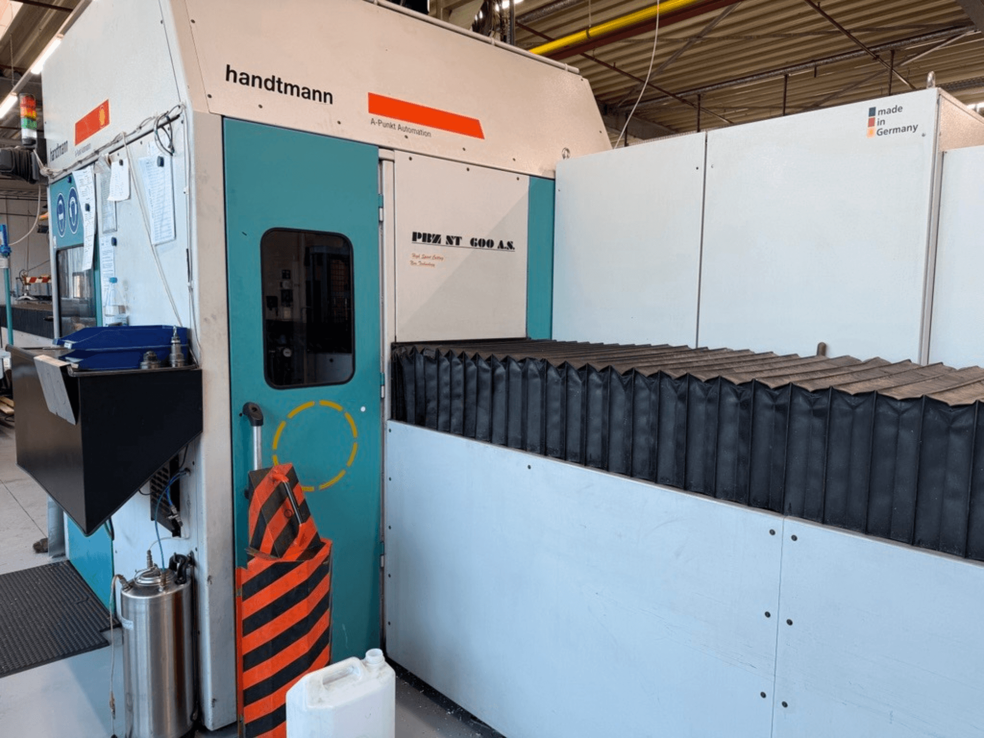 Pohled zepředu na portálovou frézku Handtmann PBZ NT 600 AS s tmavou pracovní plochou a bezpečnostními zábranami.