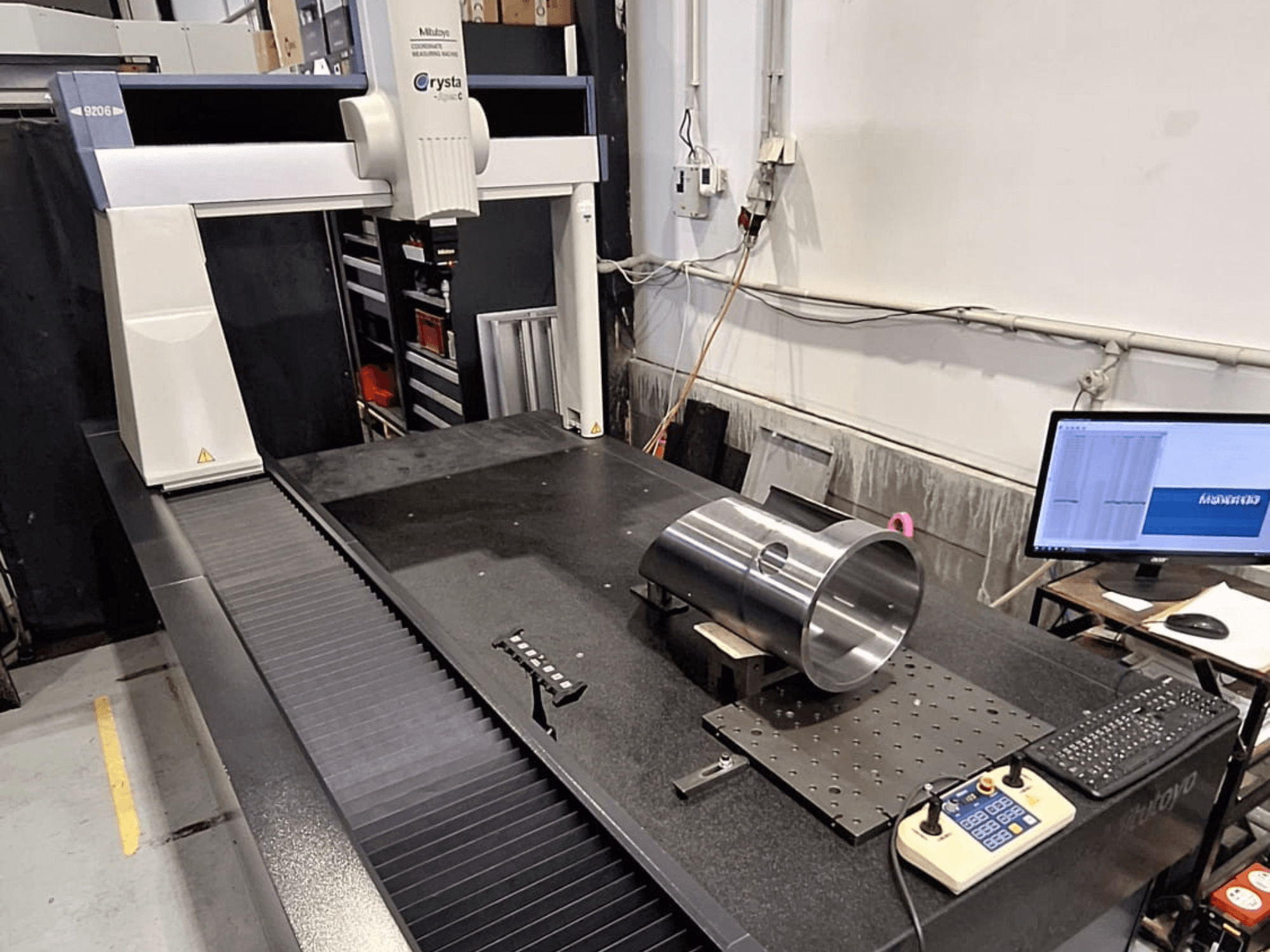 Souřadnicová měřicí souprava Mitutoyo Crysta-Apex C9206 v čelním pohledu, měření válcového kovového dílu na černé žulové povrchové desce.