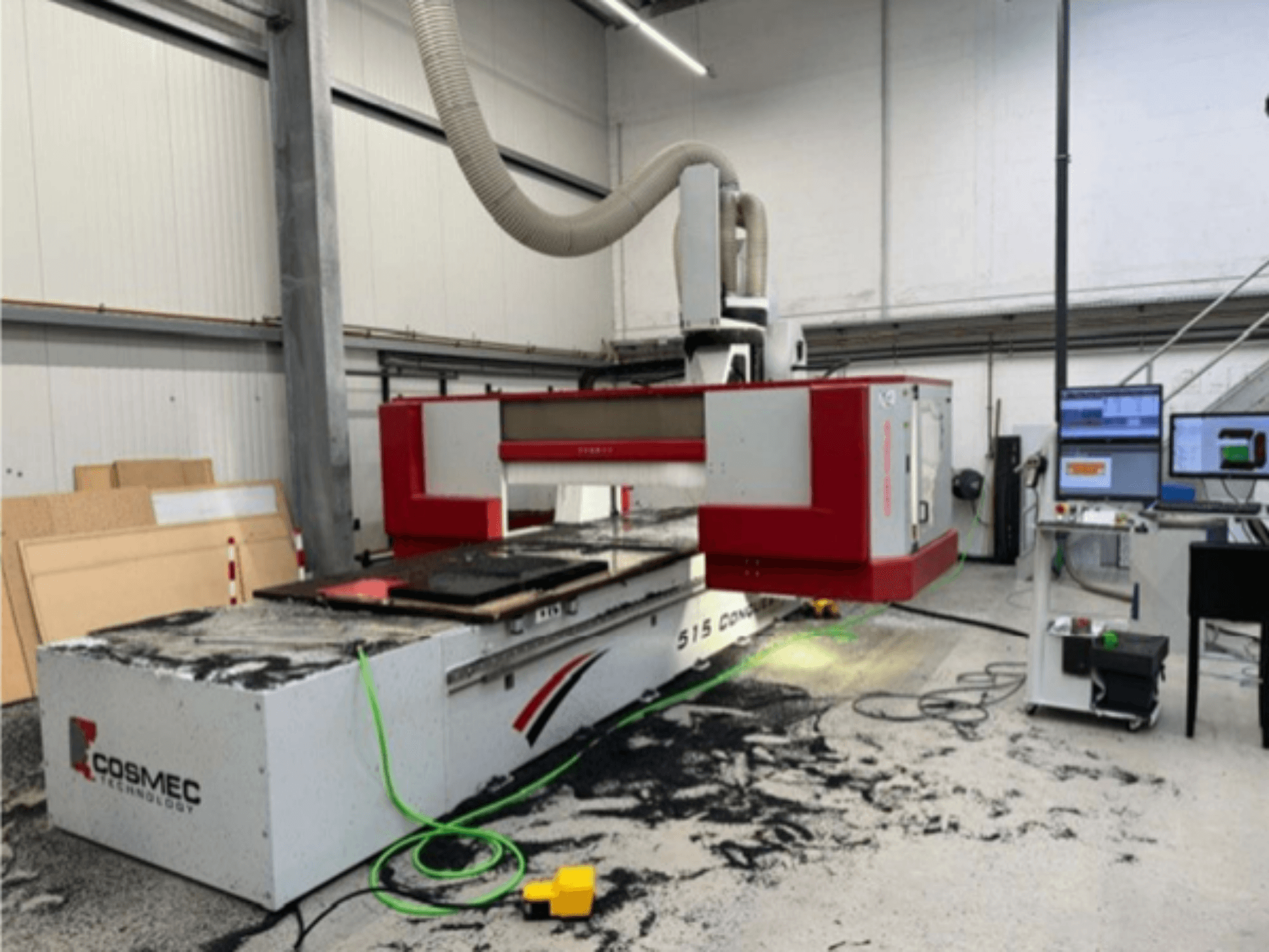 Stroj Cosmec 515 CNC v dílně s počítačovým terminálem, pohled zepředu a prach rozptýlený na povrchu.