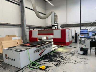 Stroj Cosmec 515 CNC v dílně s počítačovým terminálem, pohled zepředu a prach rozptýlený na povrchu.