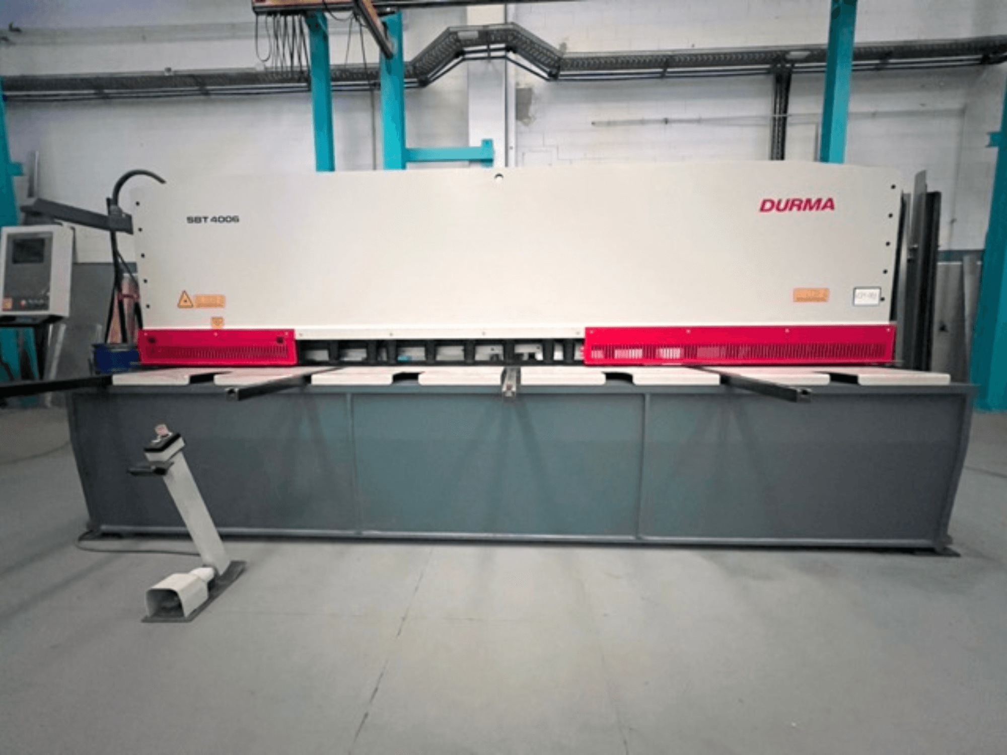 CNC stříhací stroj Durma SBT 4006 v čelním pohledu, s šedou základnou a červenými akcenty, připravený k provozu v továrním prostředí.