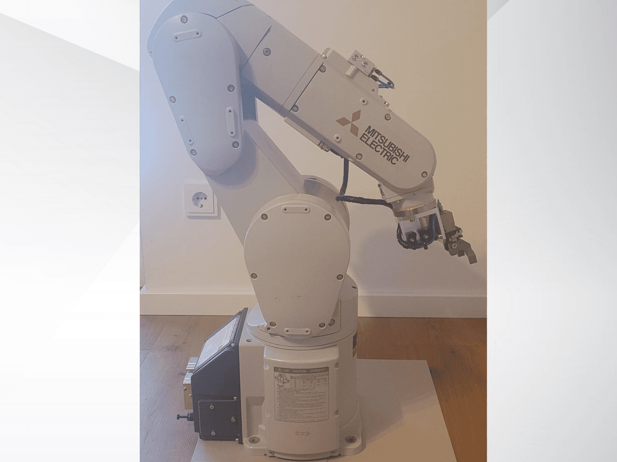 Robotické rameno Mitsubishi Electric, pohled z boku, s chapadlem a podrobným ovládacím panelem na základně pro nastavení provozu.