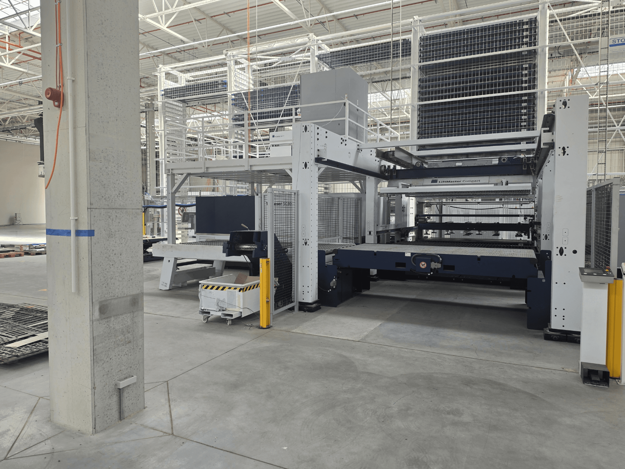 Pohled zepředu na stroj TRUMPF TruLaser 5030 fiber L76 FMC, který zachycuje vláknový laserový řezací stroj v prostorném průmyslovém prostředí.