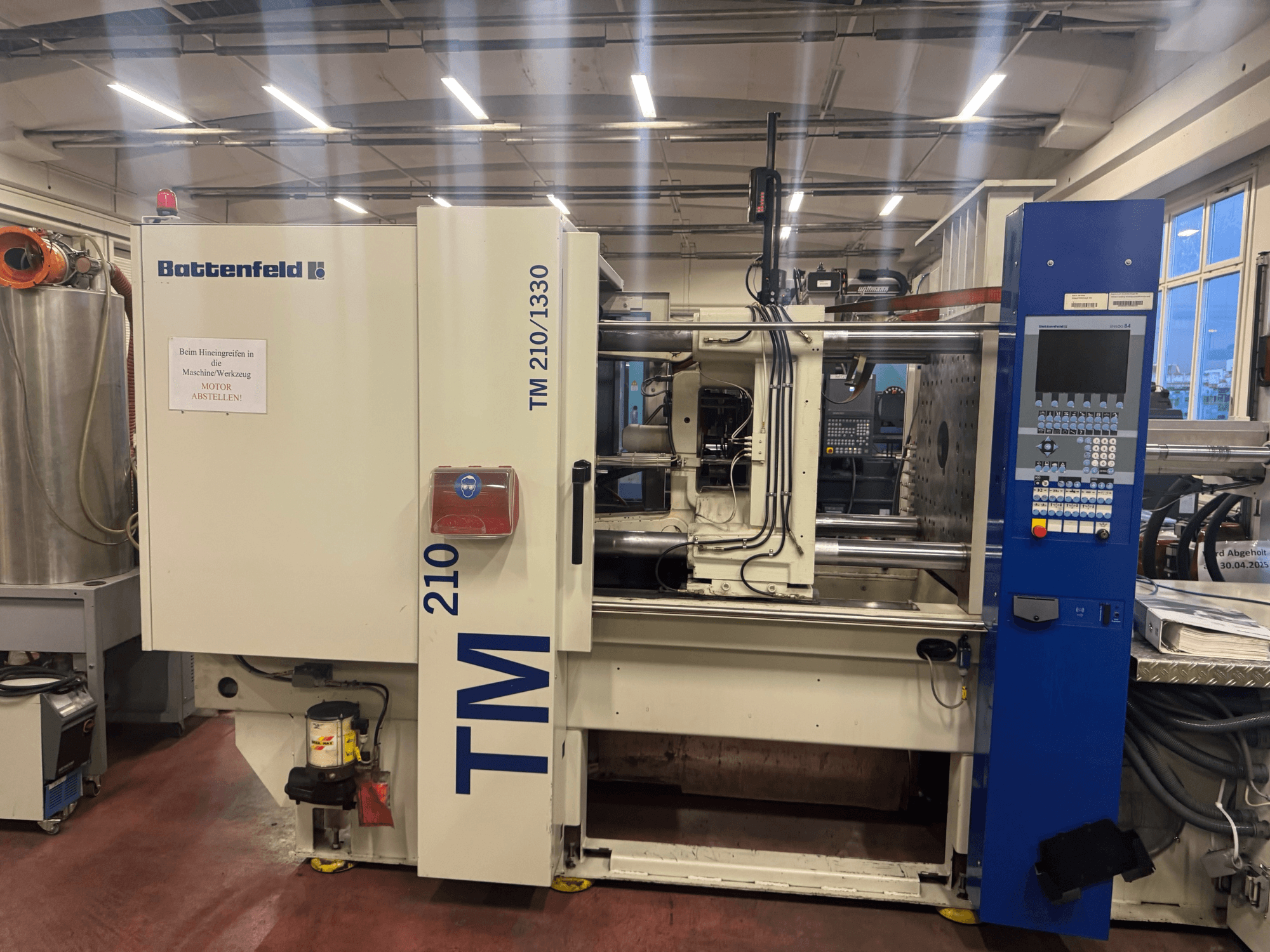 Hydraulický vstřikovací stroj Battenfeld TM 210/1330, pohled zepředu, zobrazující ovládací panel a součásti stroje.