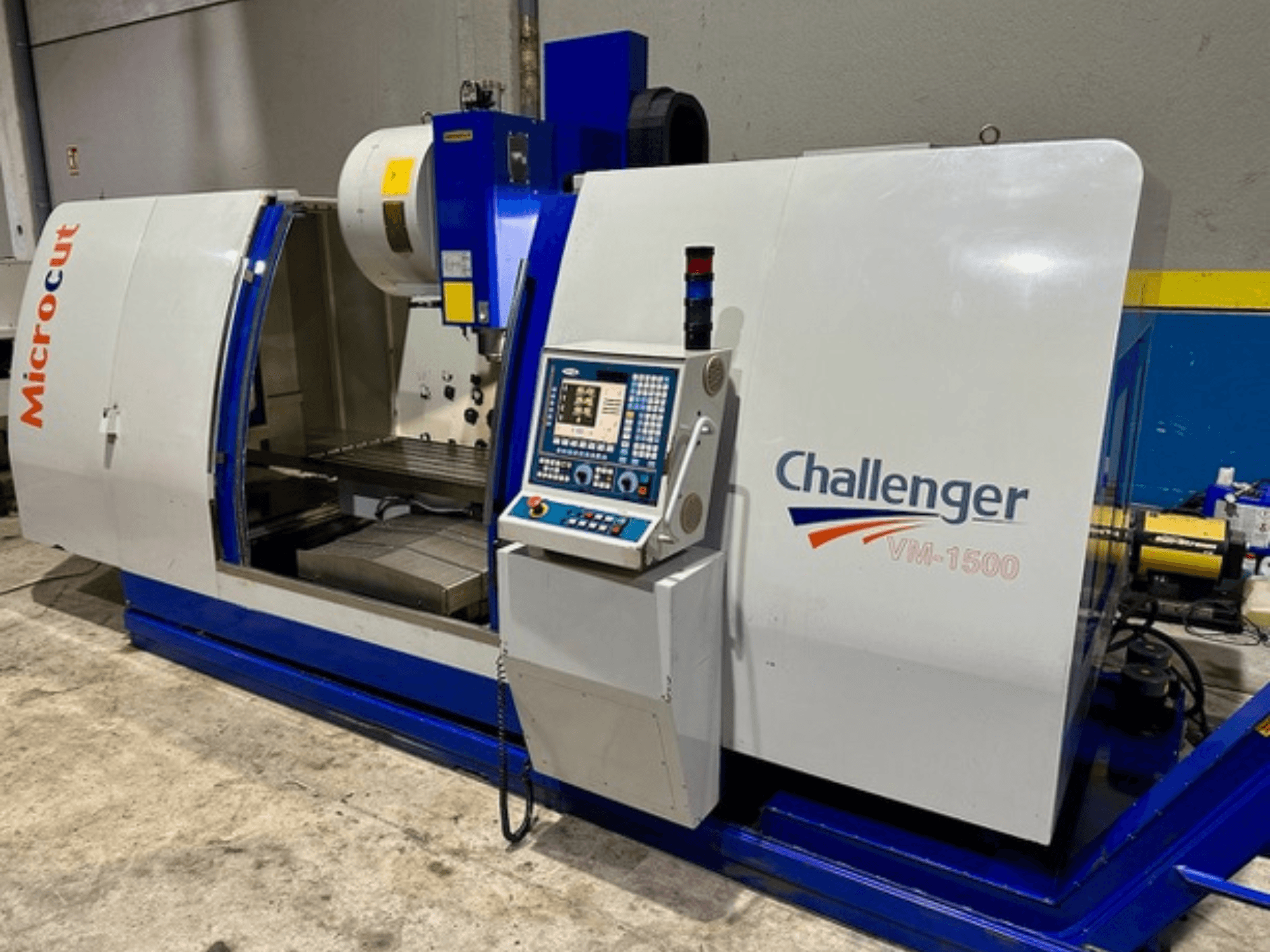 Stroj Microcut Challenger VM-1500 CNC, pohled zepředu, s ovládacím panelem, pracovním prostorem a modrou základnou.