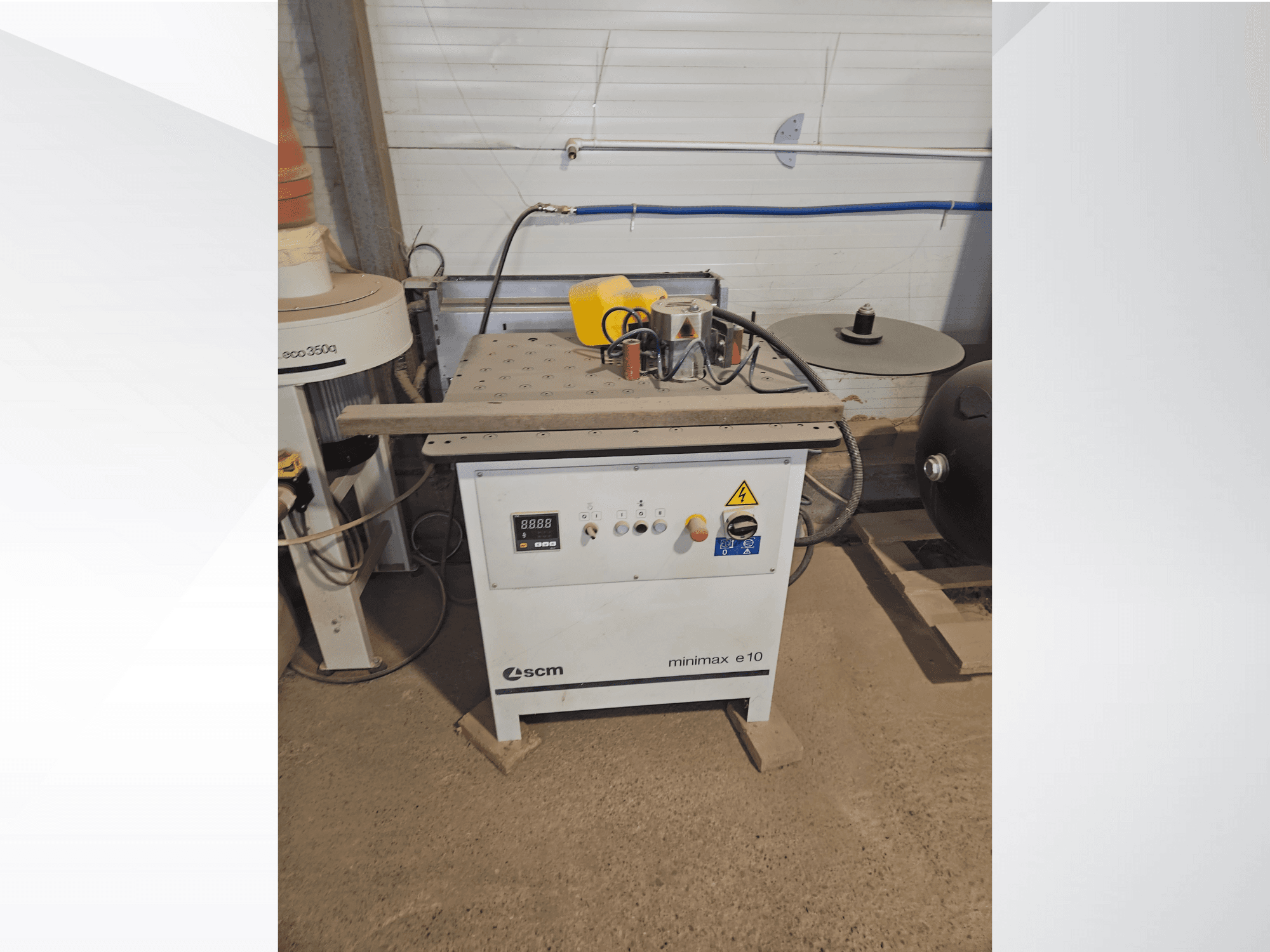 Dřevoobráběcí stroj SCM Minimax E10, pohled zepředu, s ovládacím panelem, otvorem pro prach a nastavitelnou pracovní plochou.