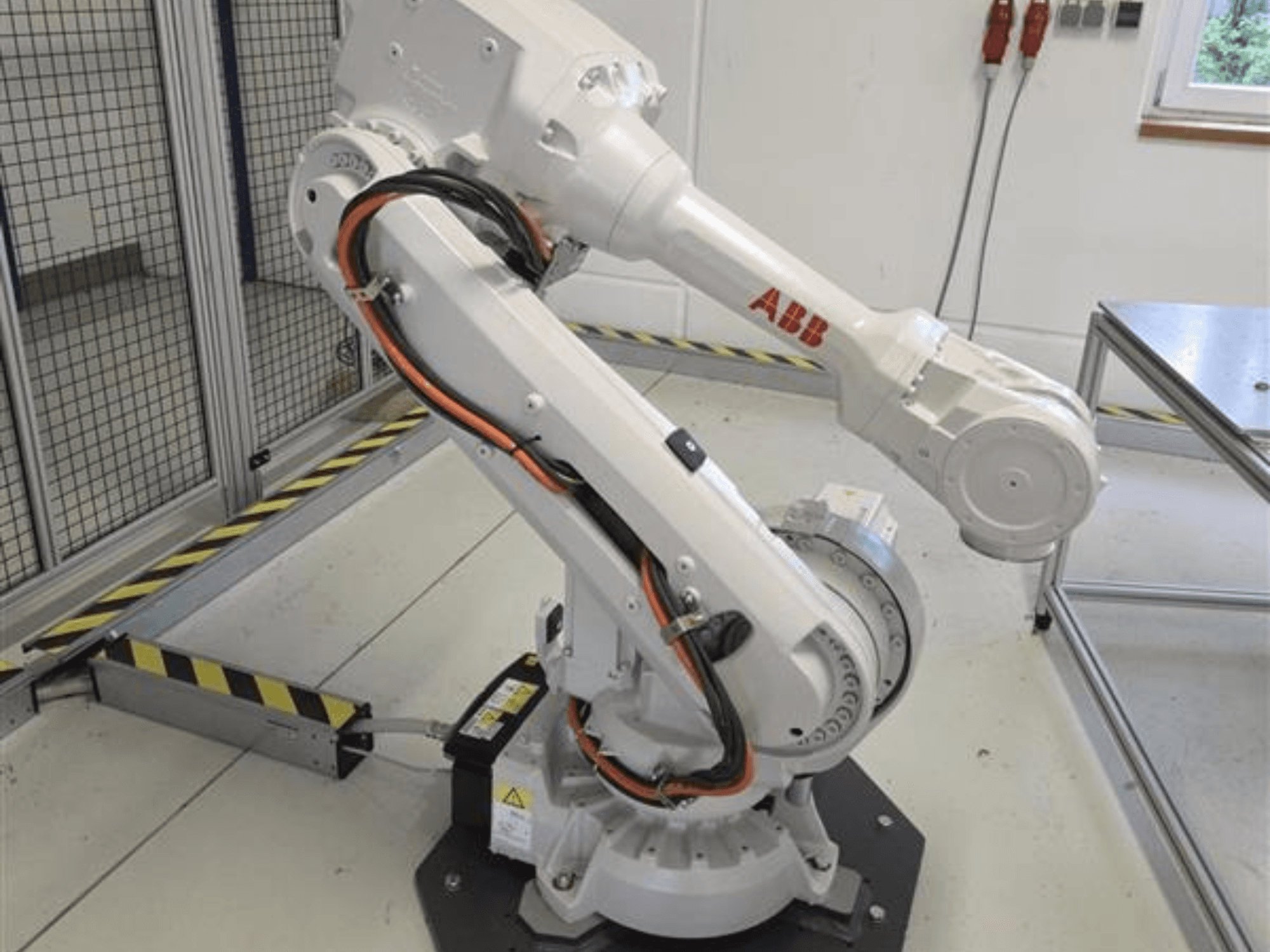 Robotické rameno ABB IRB 4600-45/2.05 v bočním pohledu, na kterém je patrná jeho kloubová konstrukce a kabely připojené k základně.