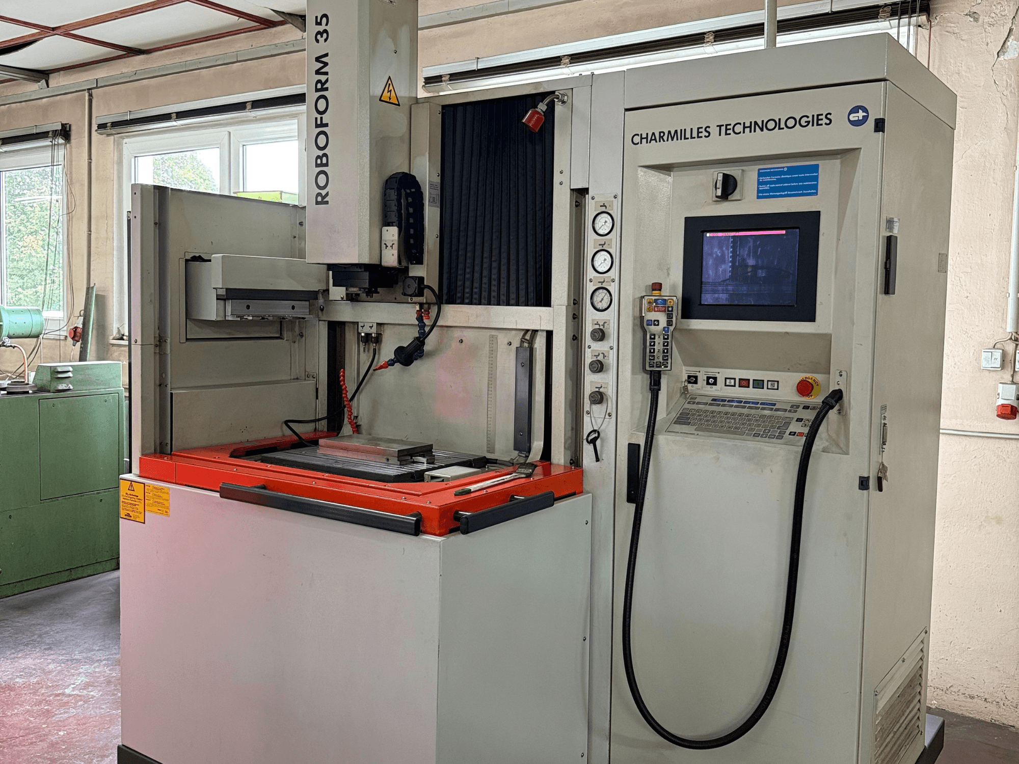 Stroj Charmilles Technologies Roboforn 35, pohled zepředu, zobrazující ovládací panel, namontované nástroje a bezpečnostní štítky.