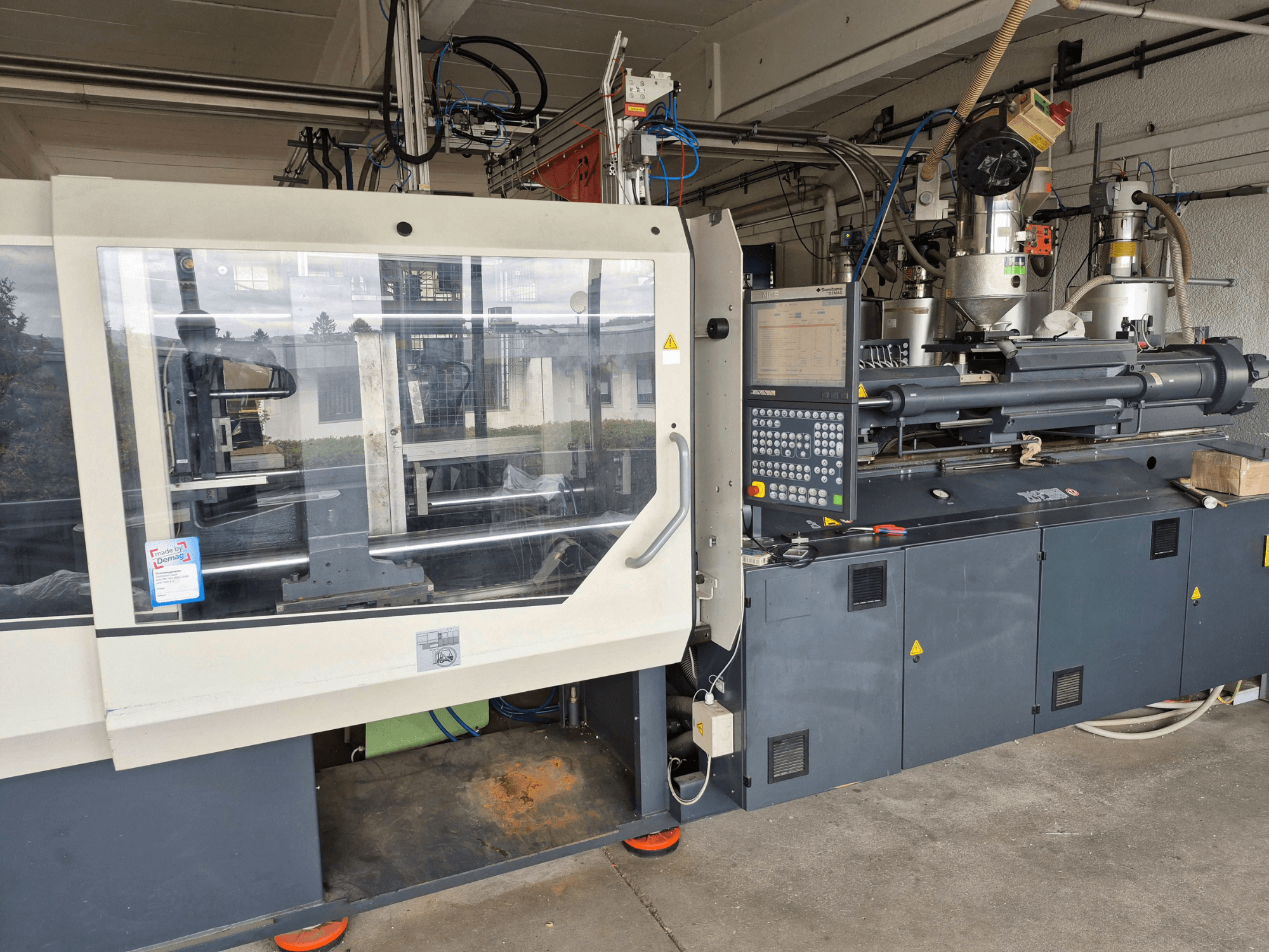Hydraulický vstřikovací stroj SUMITOMO SHI DEMAG Systec 210/580-1450, pohled zepředu s ovládacím panelem a viditelnými součástmi.