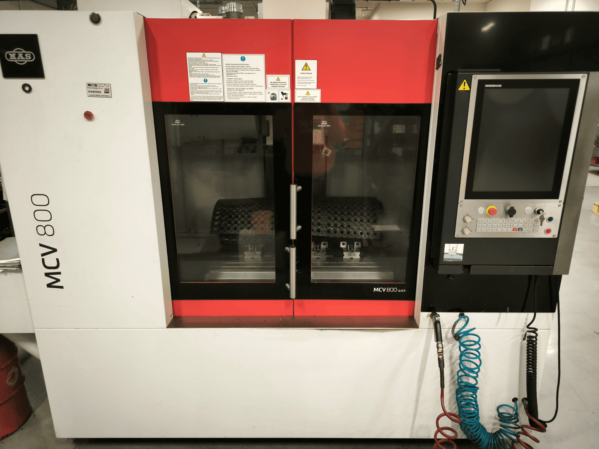 Vertikální obráběcí centrum KOVOSVIT MAS MCV 800 QUICK, pohled zepředu s ovládacím panelem a dvojitými skleněnými dveřmi, které ukazují pracovní prostor.