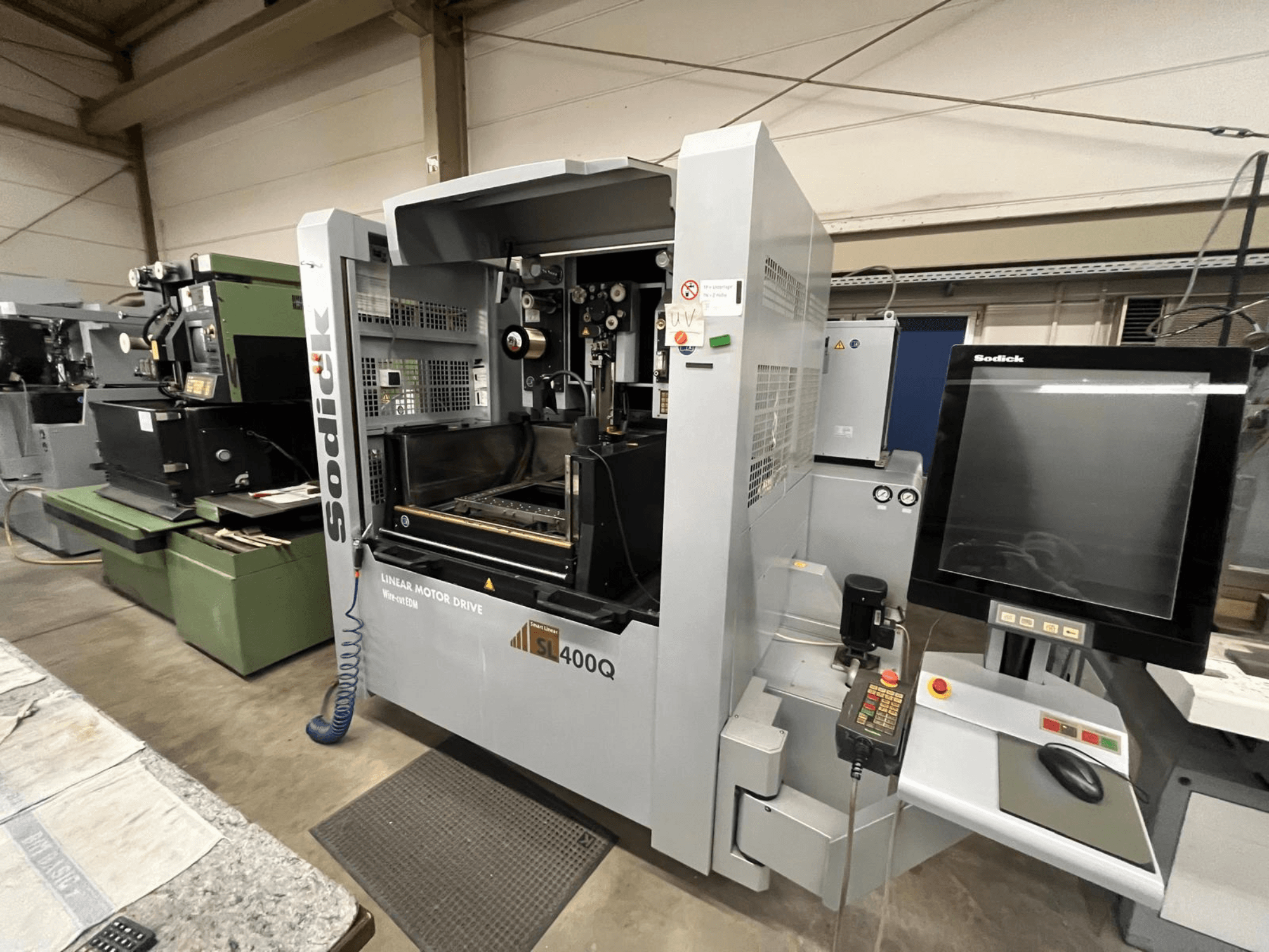 CNC stroj Sodick SL400Q s lineárním motorovým pohonem, pohled zepředu s digitálním ovládacím panelem a displejem v dílenském prostředí.