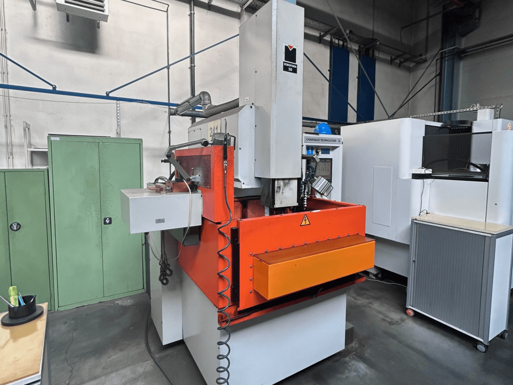 Pohled zepředu na elektroerozivní stroj CHARMILLES ROBOFORM 50 s oranžovým panelem, ovládacím rozhraním a okolním vybavením.