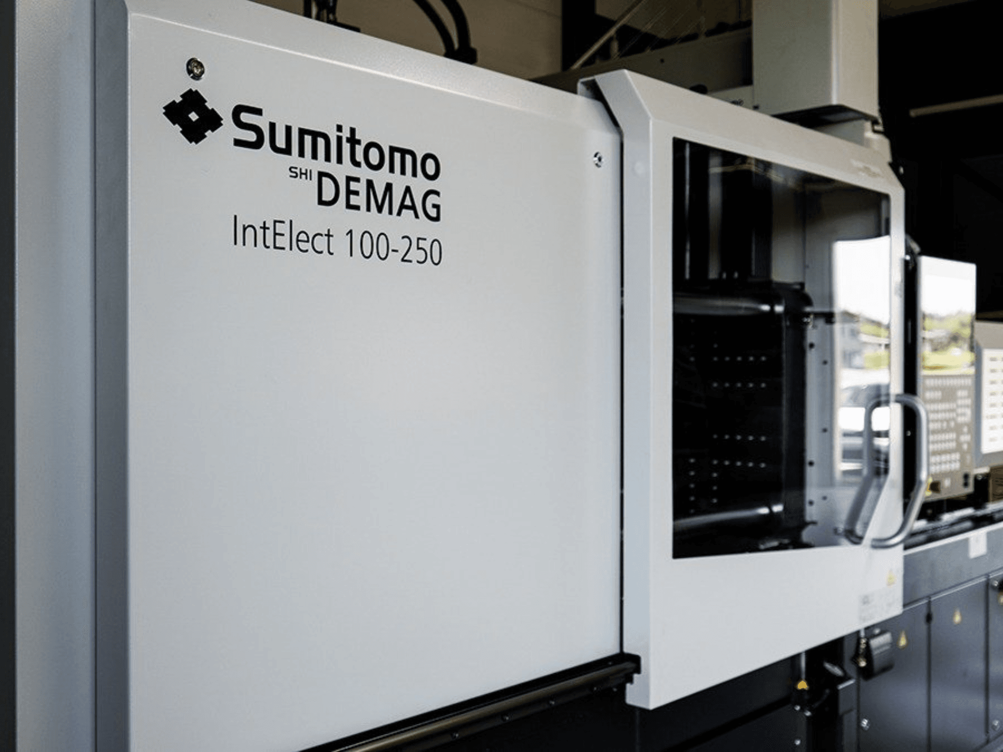 Pohled zepředu na elektrický vstřikovací lis SUMITOMO SHI DEMAG IntElect 100/250 s ovládacím panelem a bezpečnostními prvky.