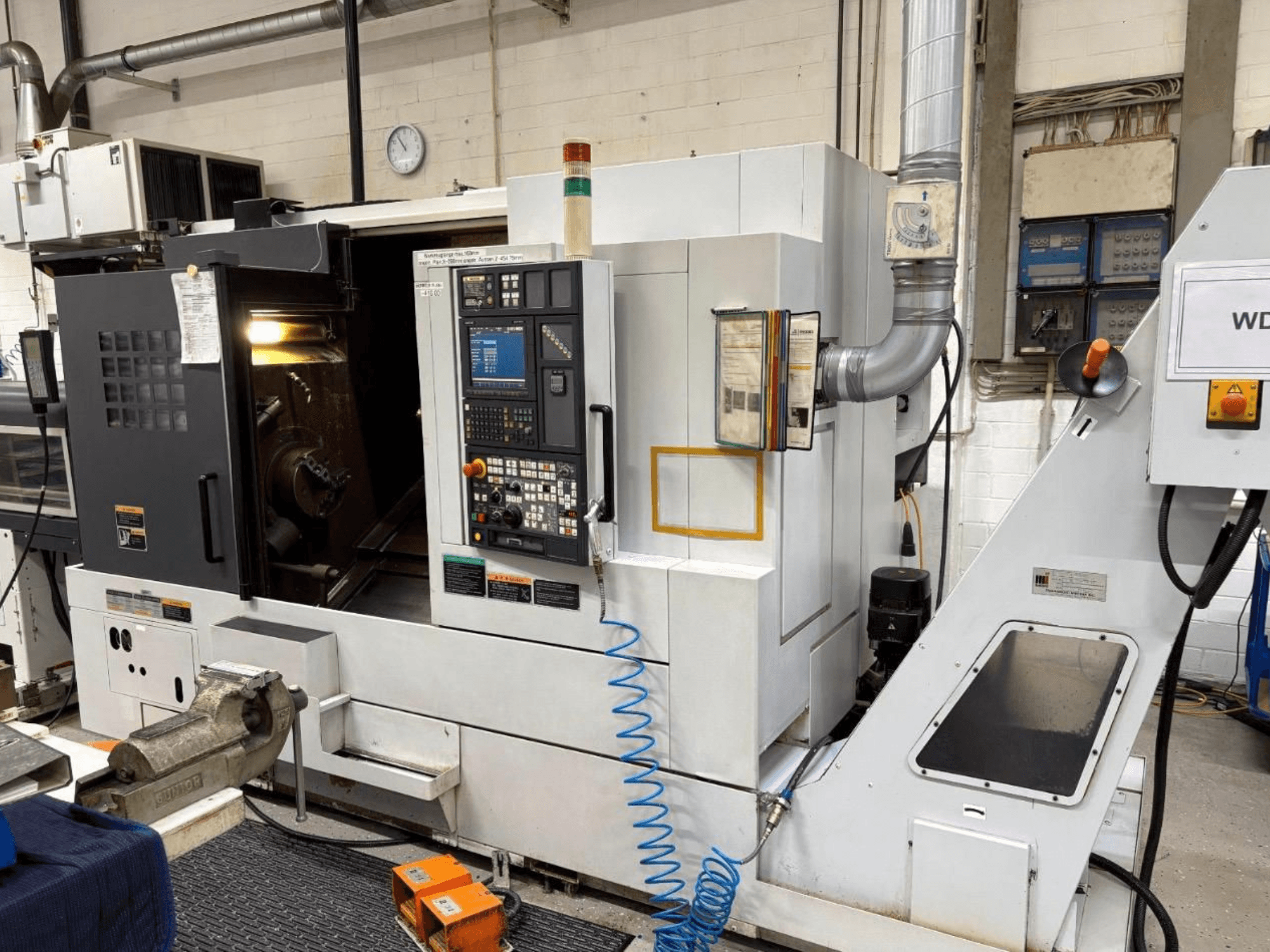 Soustružnické centrum MORI SEIKI NL 2500 SY, pohled zepředu, zobrazující ovládací panel a obráběcí plochu. Viditelný chladicí systém a příslušenství.