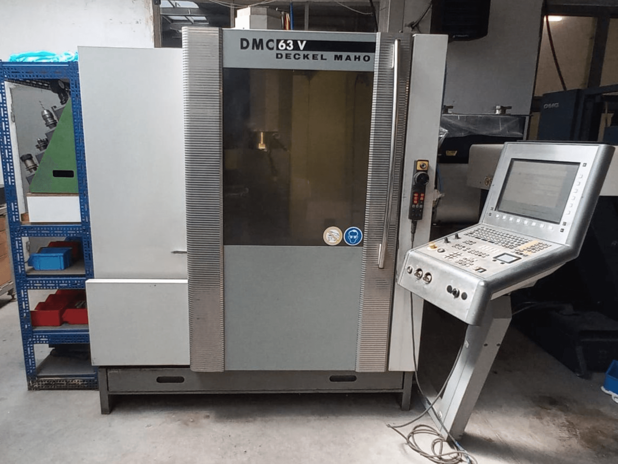 Pohled zepředu na vertikální obráběcí centrum DMG DECKEL MAHO DMC 63V s ovládacím panelem a viditelným pracovním prostorem.