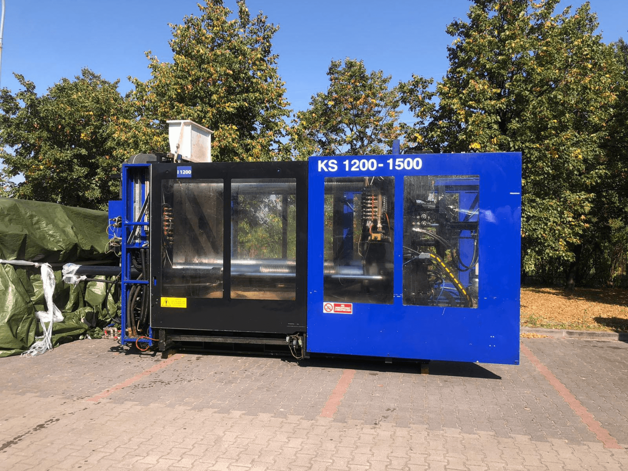 Hydraulický vstřikovací stroj ITALTECH KS 1200 8300 ES, boční pohled, ukázka ovládacích prvků a detailů stroje v parkovém prostředí.