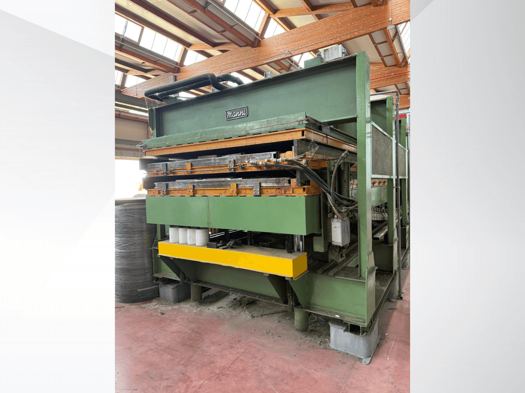 Hydraulický lis Manni, boční pohled, se zeleným kovovým tělem, žlutou základnou a viditelnými hydraulickými vedeními.