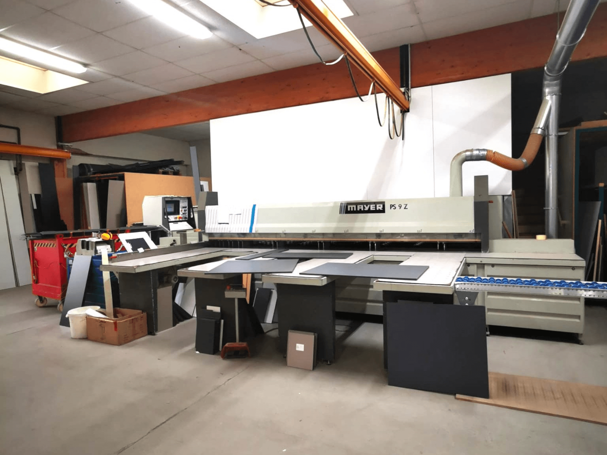 Řezací stroj MAYER PS9 Z v dílně, pohled zepředu, s viditelnými různými materiály a dopravníkovým systémem.