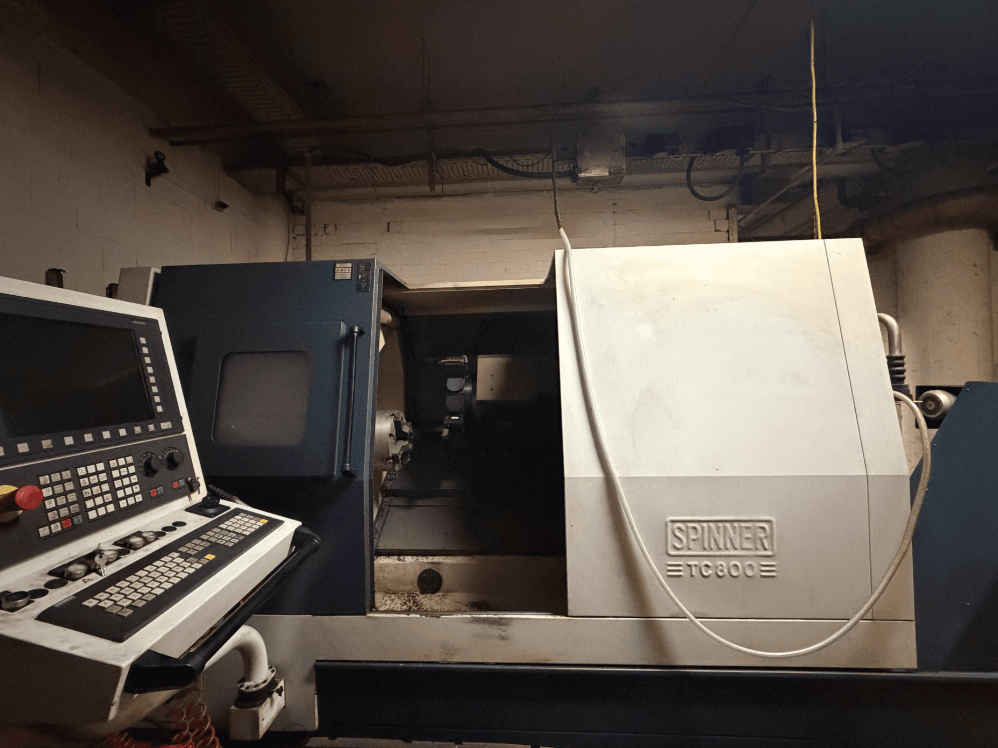 Horizontální soustruh SPINNER TC800, pohled zepředu s viditelným ovládacím panelem a mírně odkrytým vnitřkem stroje.