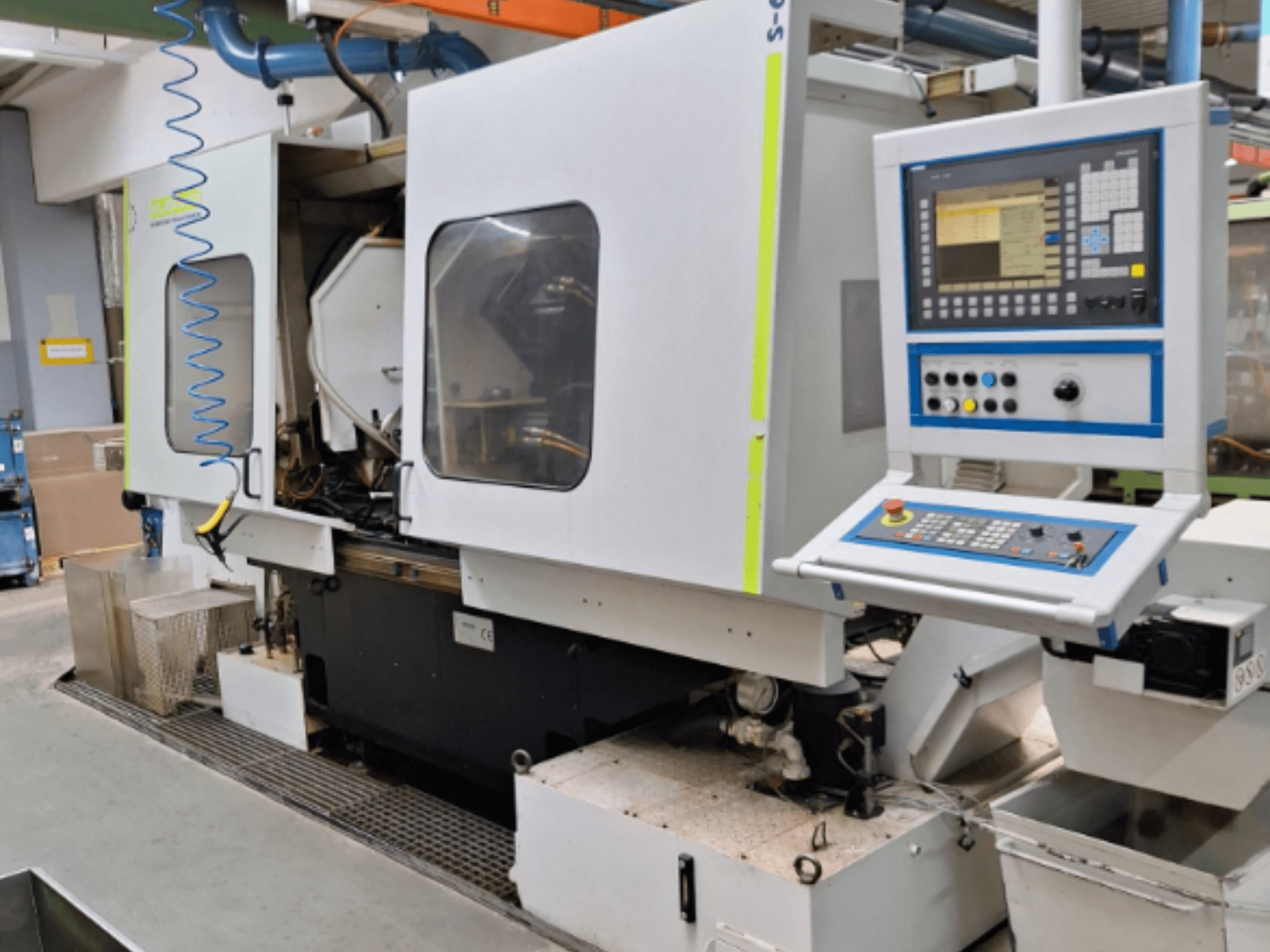 Průmyslová frézka s ovládacím panelem, pohled z boku, se dvěma komorami a viditelnými přípojkami potrubí.