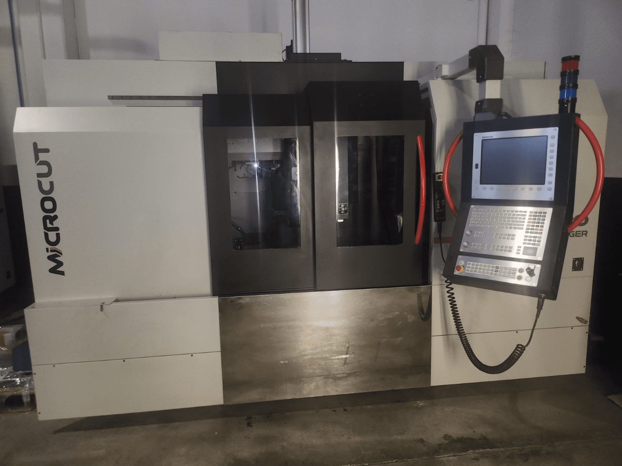 Stroj Microcut CNC při pohledu zepředu; má ovládací panel, dvě okna, průmyslový design a kovovou povrchovou úpravu.
