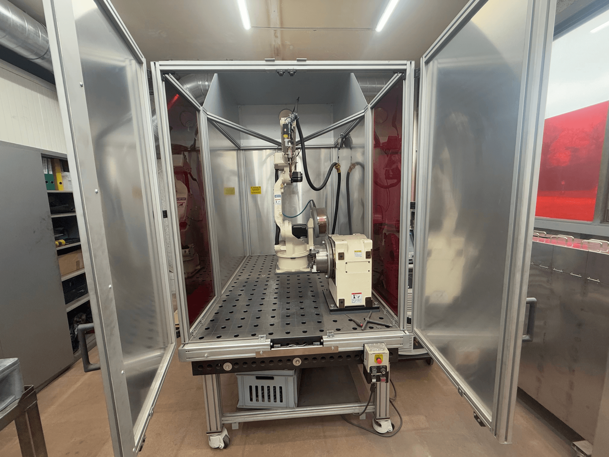 Svařovací robot OTC Daihen EASY ARC V02.04 v kovové skříni, pohled zepředu, s kloubovým ramenem a ovládacím panelem.