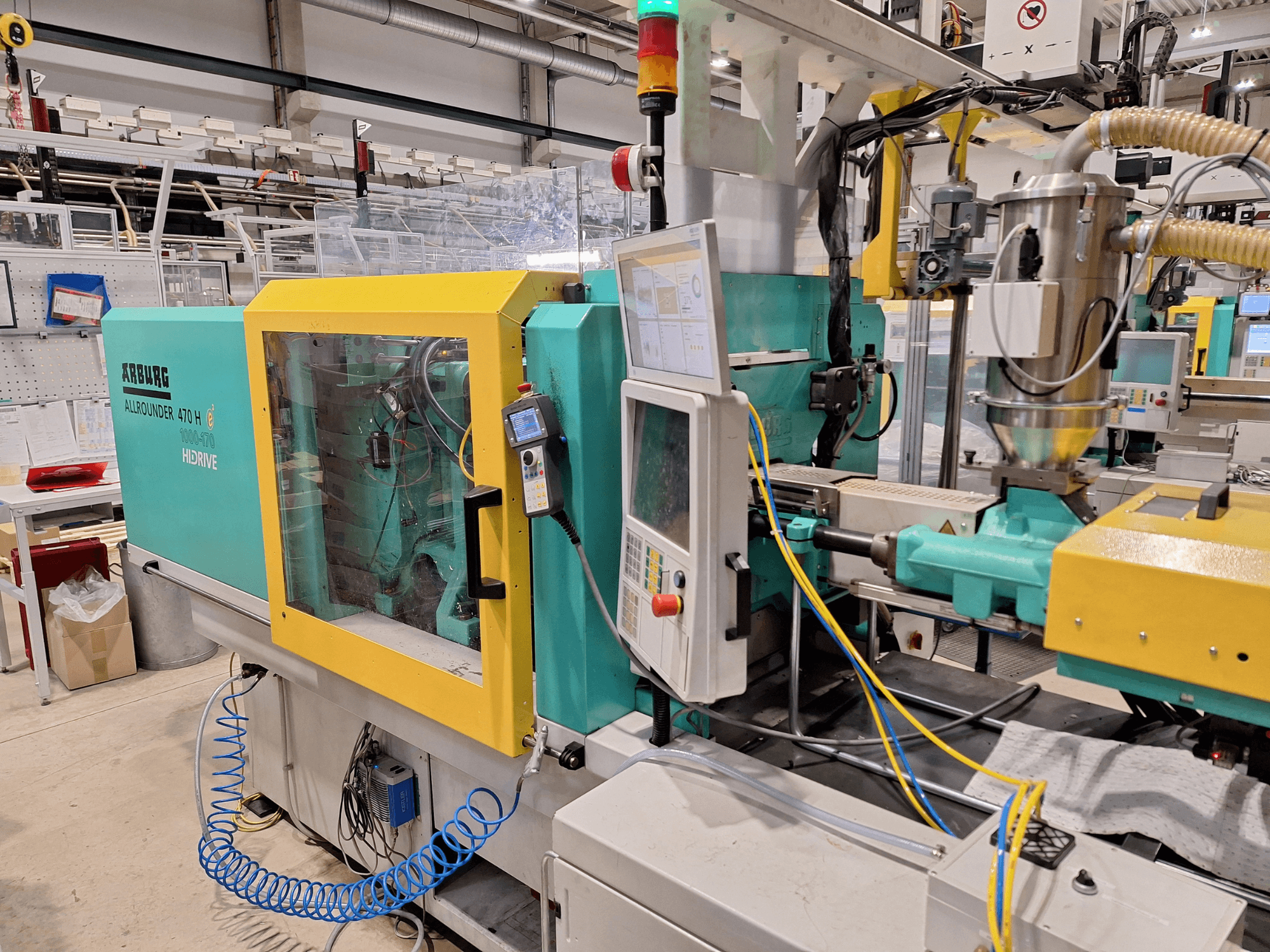 Hydraulický vstřikovací stroj Arburg 470 H 1000-170, boční pohled na ovládací panel a podávací systém.