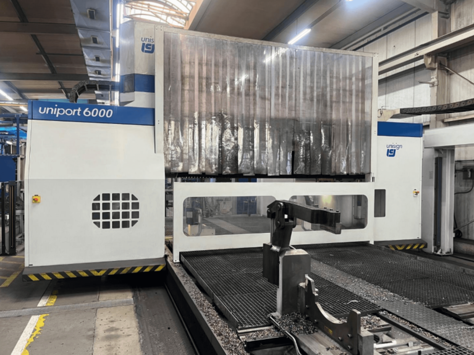 Portálová frézka Unisign uniport 6000, pohled zepředu, konstrukce stroje a řezný prostor s kovovými hoblinami.