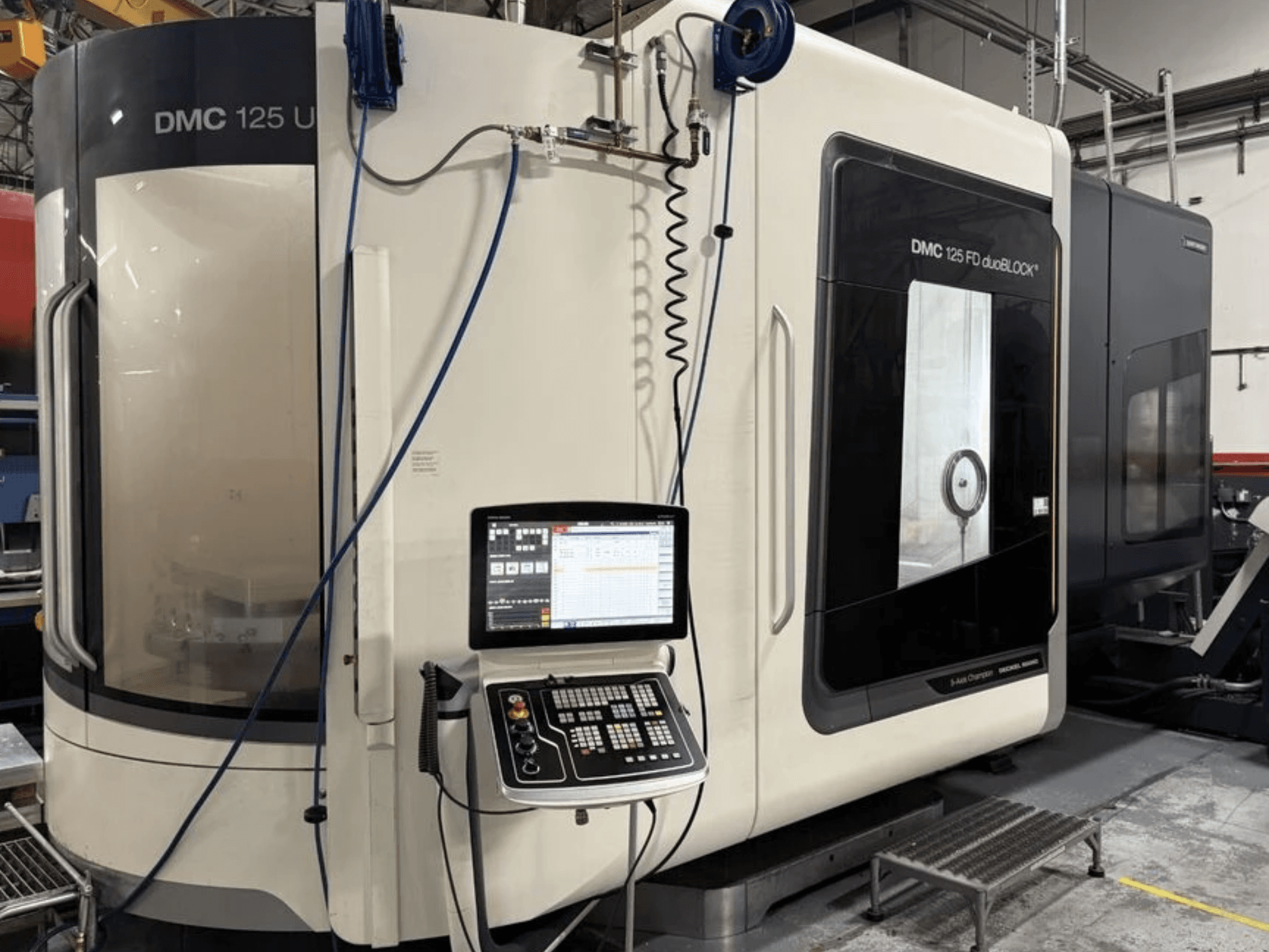 Univerzální obráběcí centrum DMG MORI DMC 125 U duoBLOCK, pohled zepředu s ovládacím panelem a odrazivými plochami.