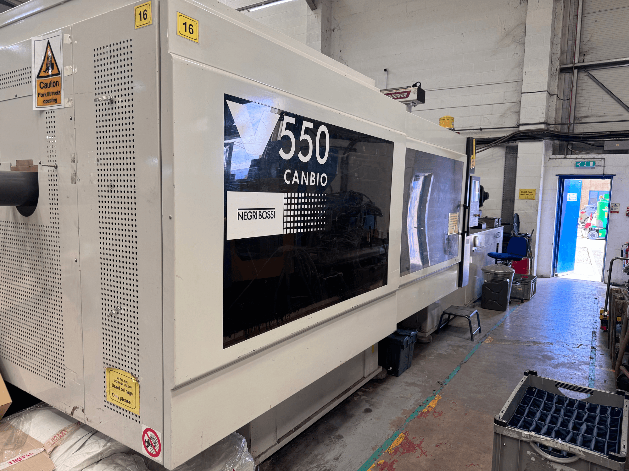Hydraulický vstřikovací stroj Negri Bossi 5500H-4250, pohled zepředu s ovládacím panelem a výstražnými značkami.