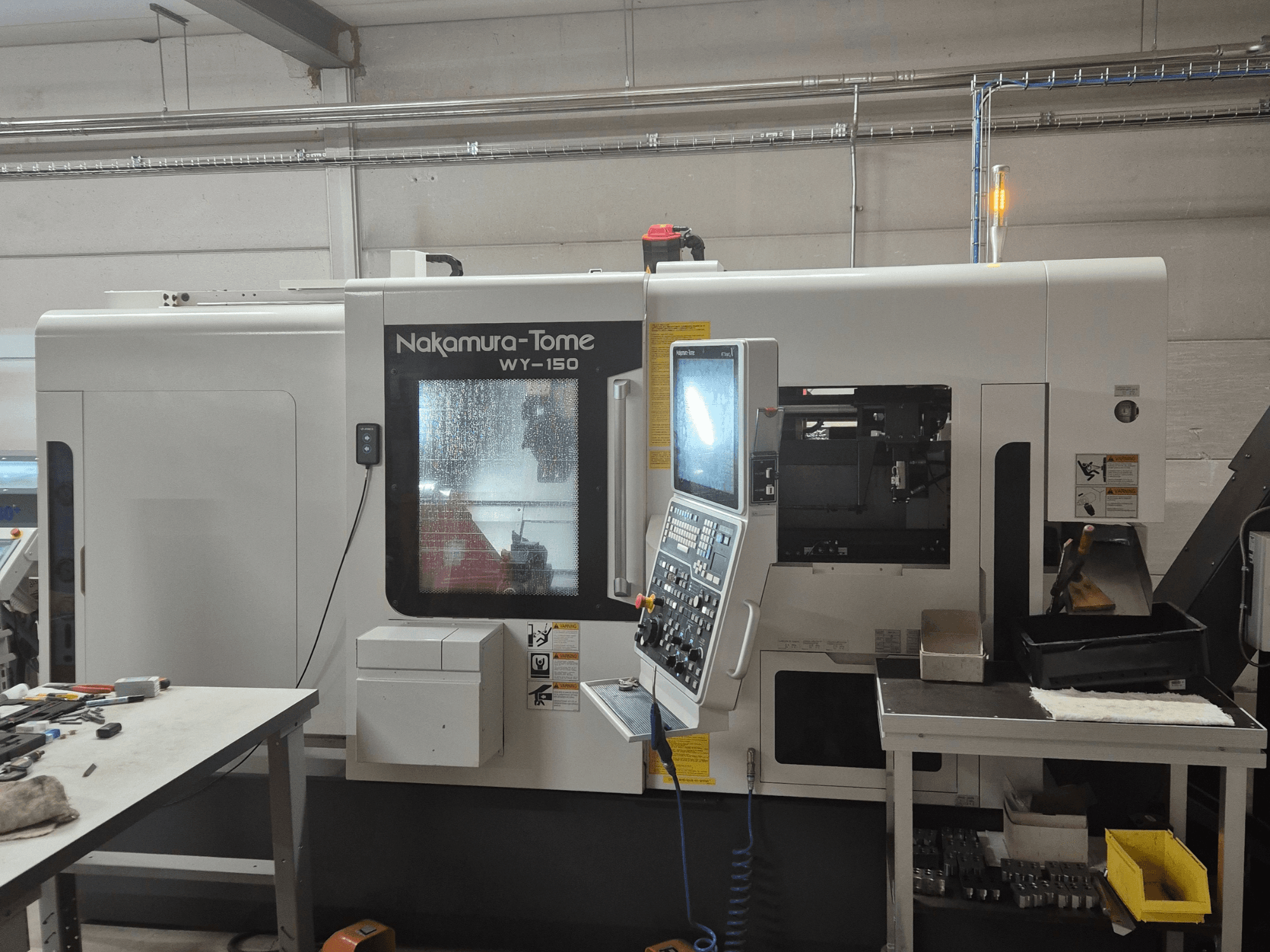 CNC soustruh Nakamura-Tome WY-150 v bočním pohledu, s ovládacím panelem, průhledovým oknem a viditelným pracovním prostorem.