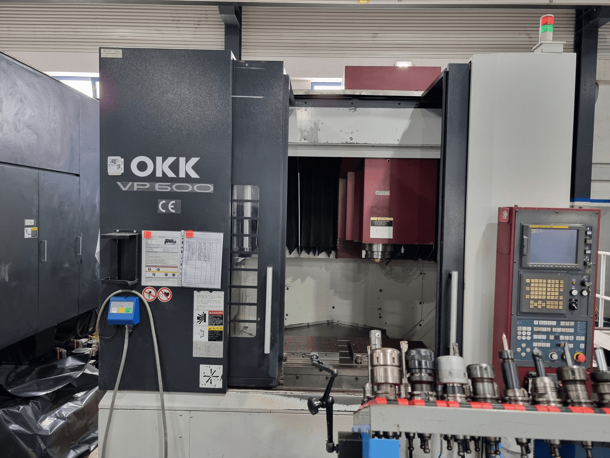 Vertikální obráběcí centrum OKK VP600 z čelního pohledu, na kterém je vidět ovládací panel a držáky nástrojů na stojanu.